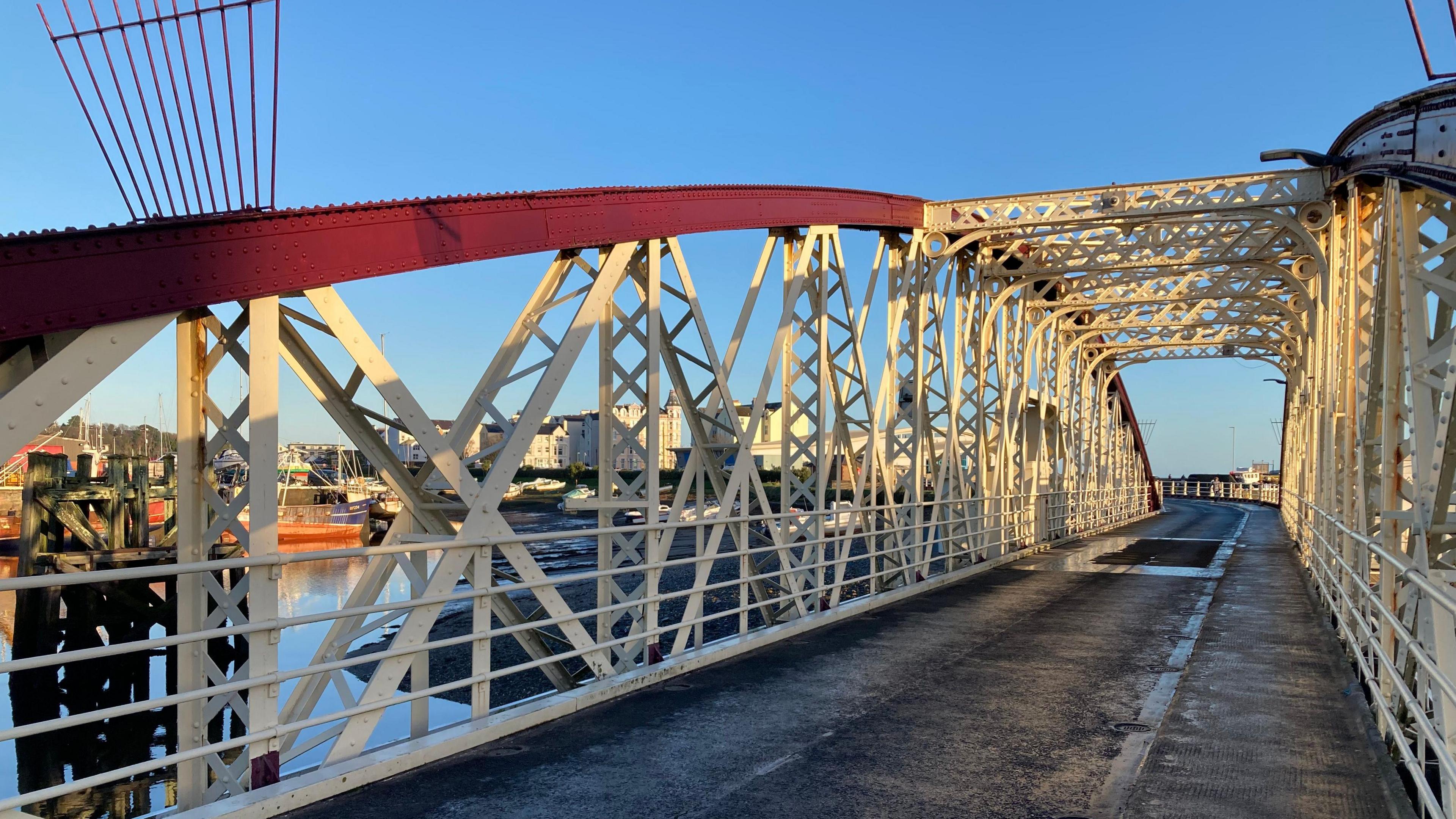 The road on the Swing Bridge, which has an arching red metal structure with white metal railings and a road.