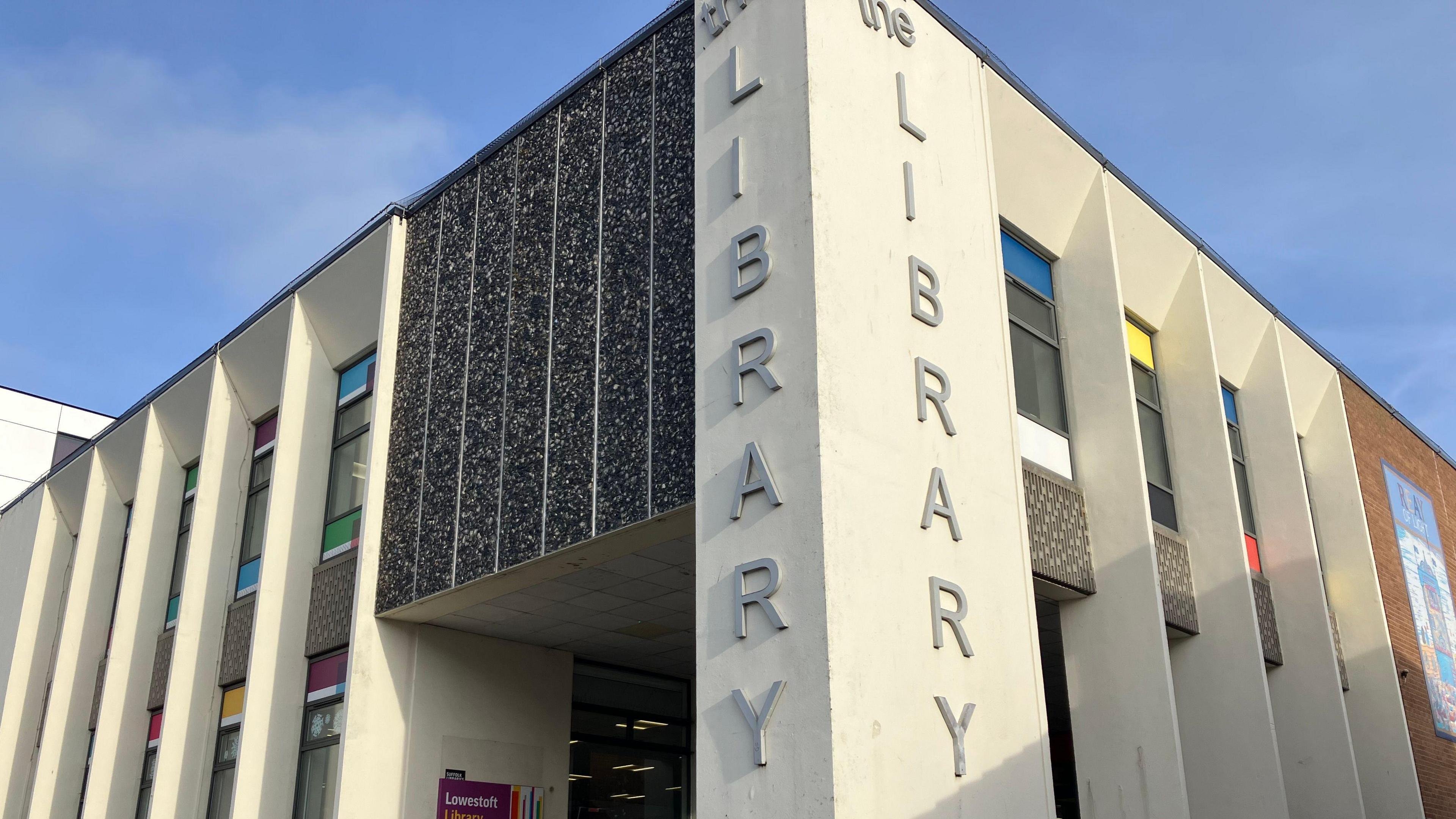 The entrance to Lowestoft Library with the words 'The Library' written in large silver letters on a white, Piet Mondrian-inspired facade    