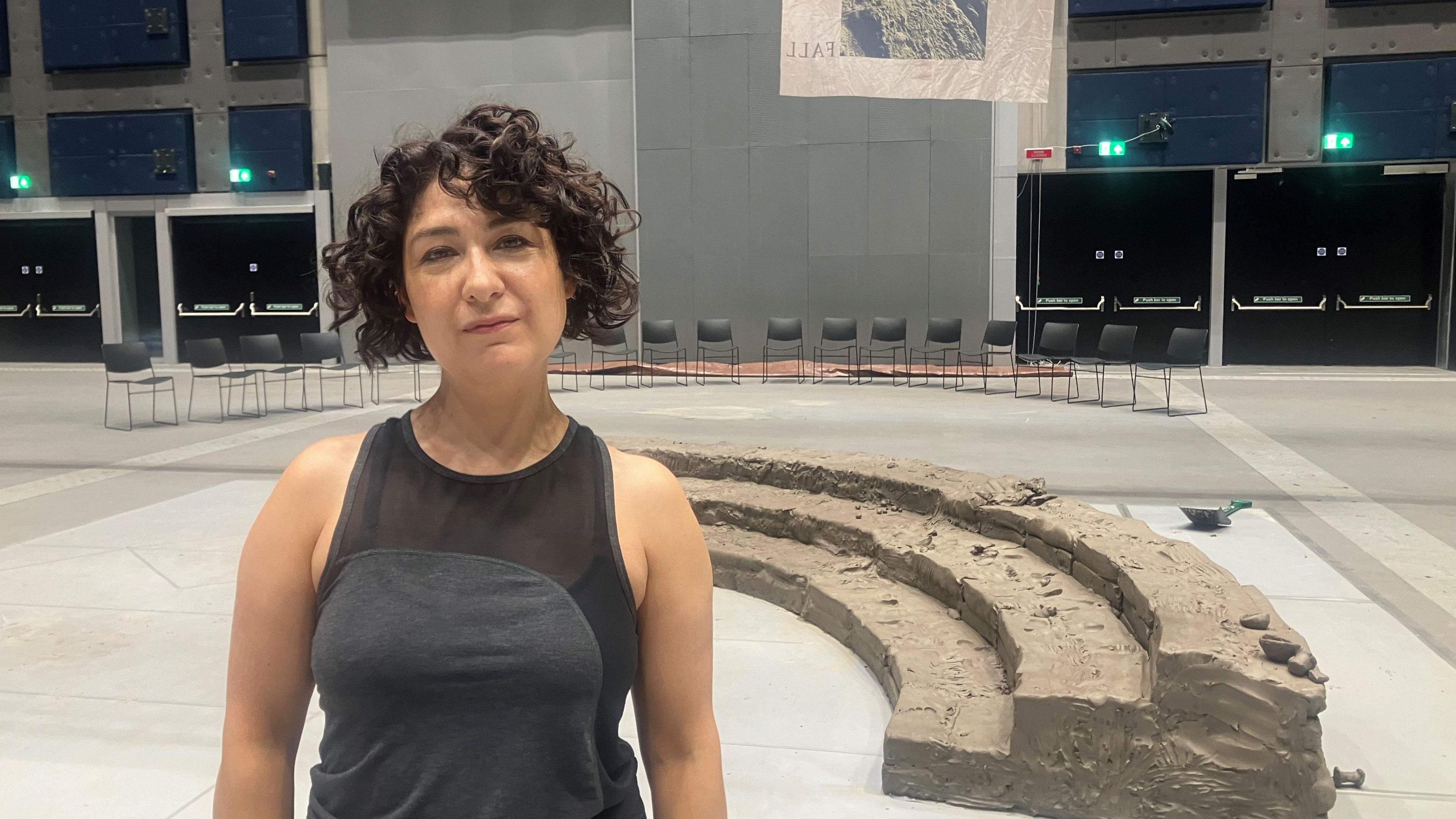 Jenny Jackson stands in front of clay amphitheatre, which she is developing as part of an art project