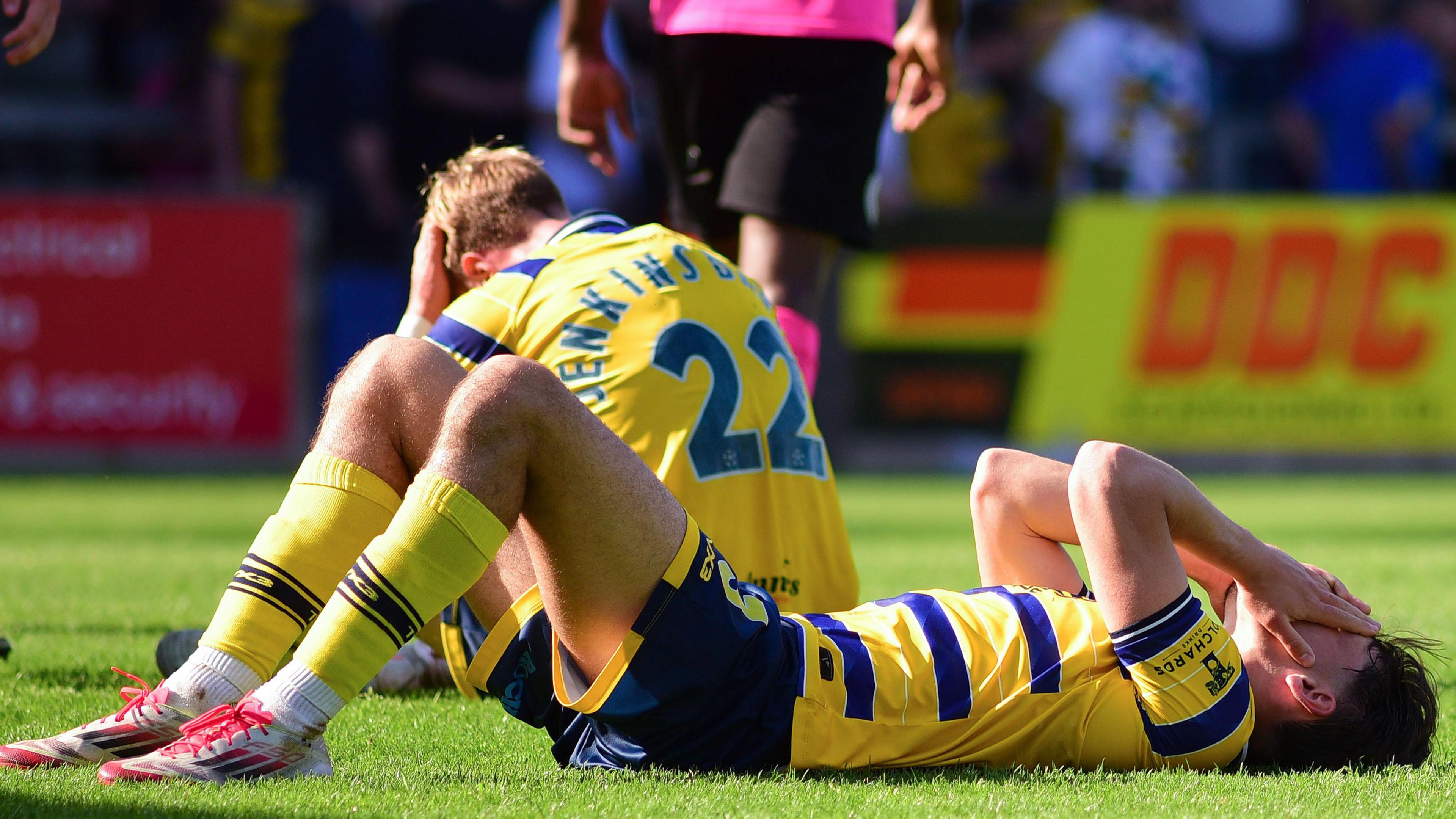 Torquay's players lie on the ground dejected after losing their play-off semi-final to Boreham Wood