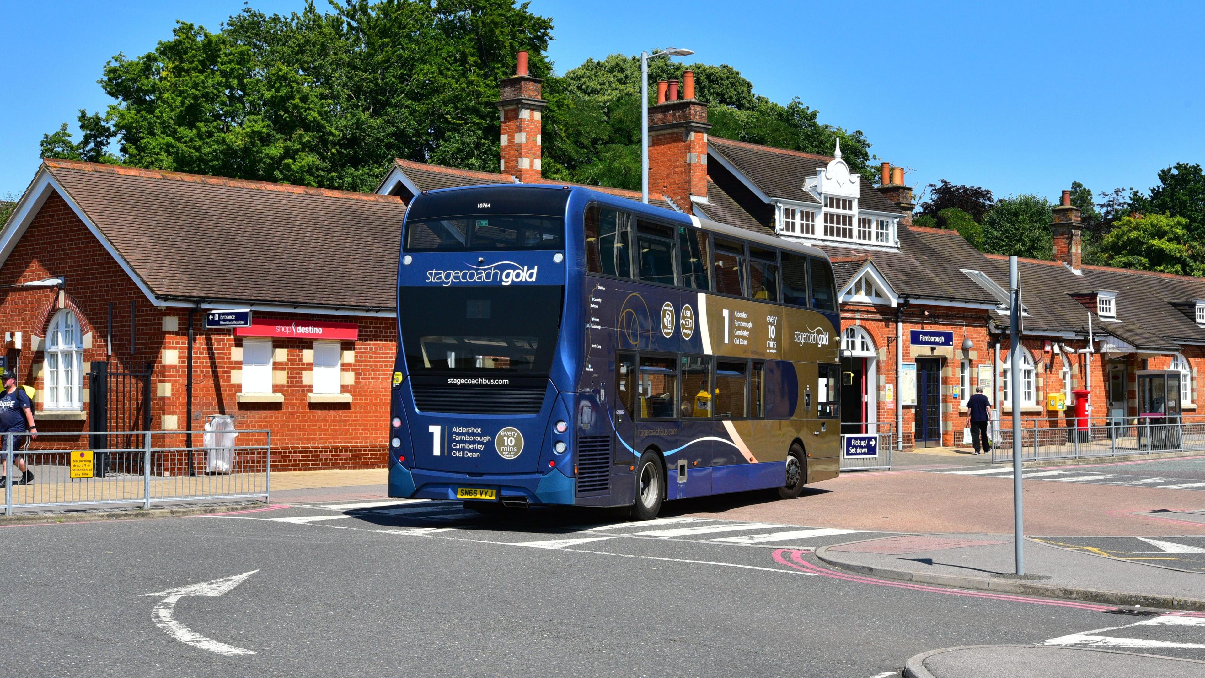 A blue and gold double decker bus outside Farnborough rail station