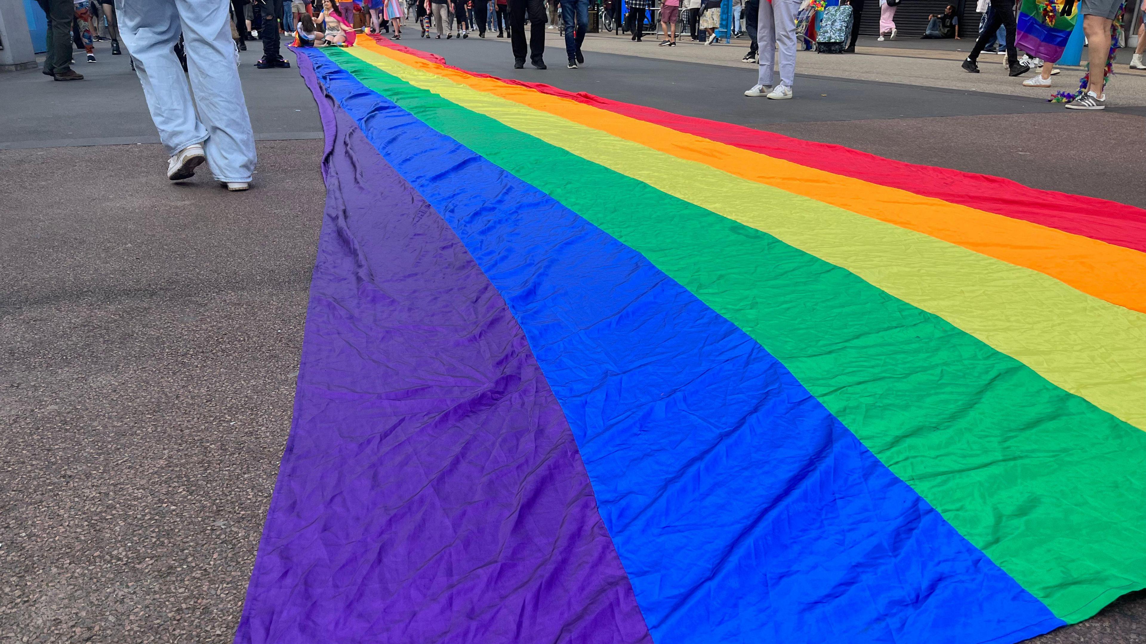 A rainbow pride flag laid out on the pavement.