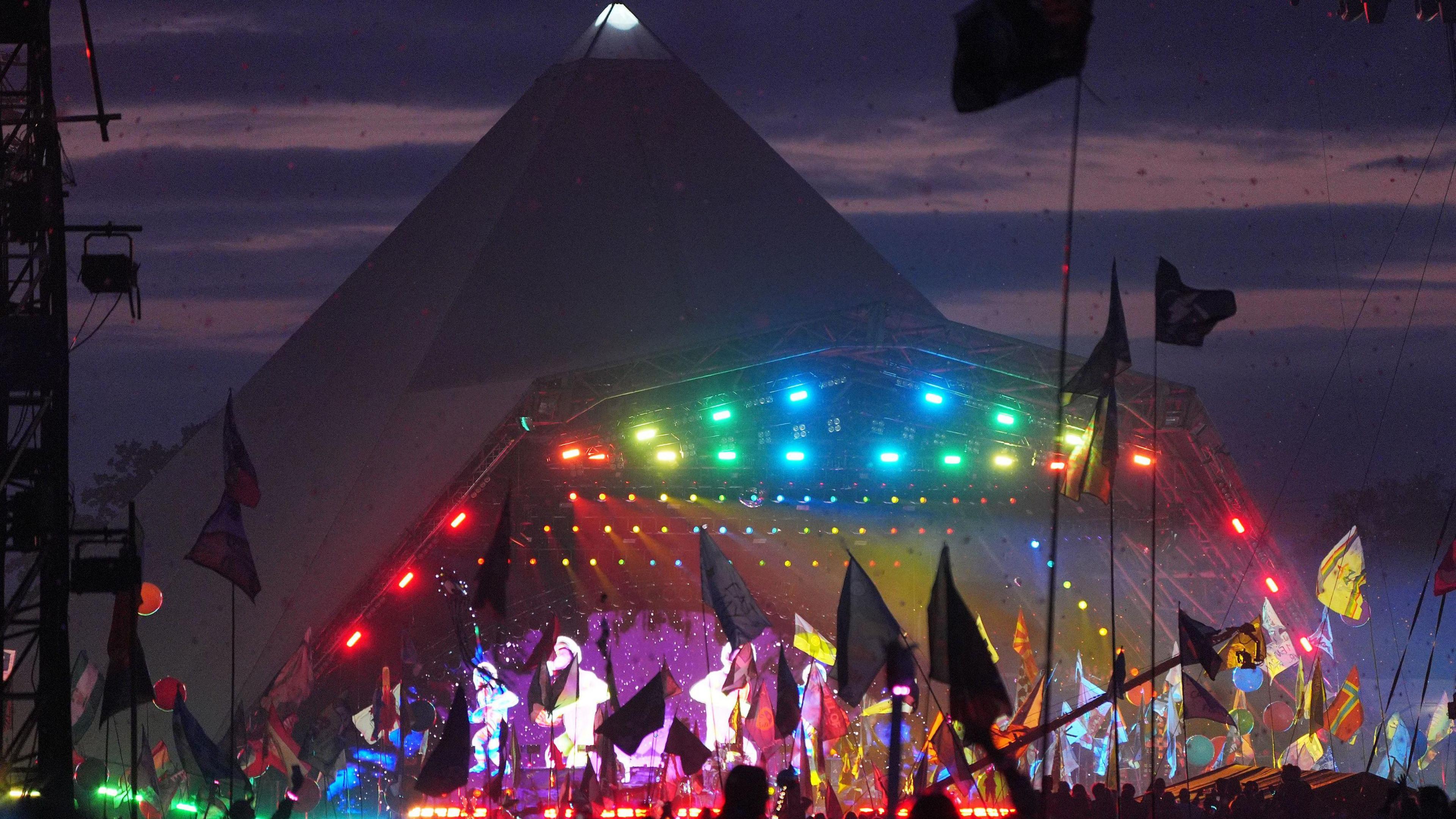 Crowds wave flags and dance to Coldplay at the Pyramid Stage at Glastonbury Festival.