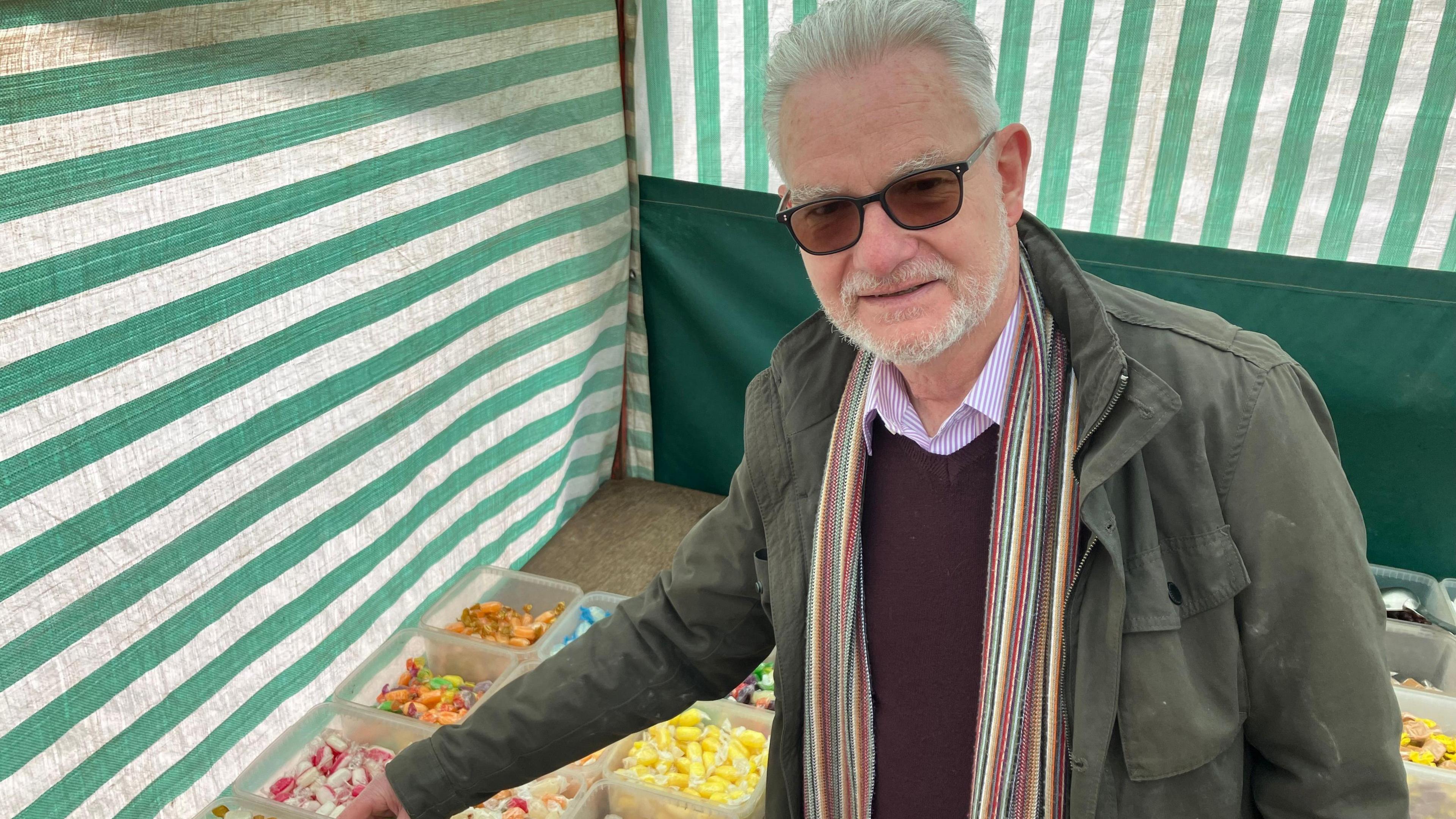 Man with white beard chooses sweets at the stall 