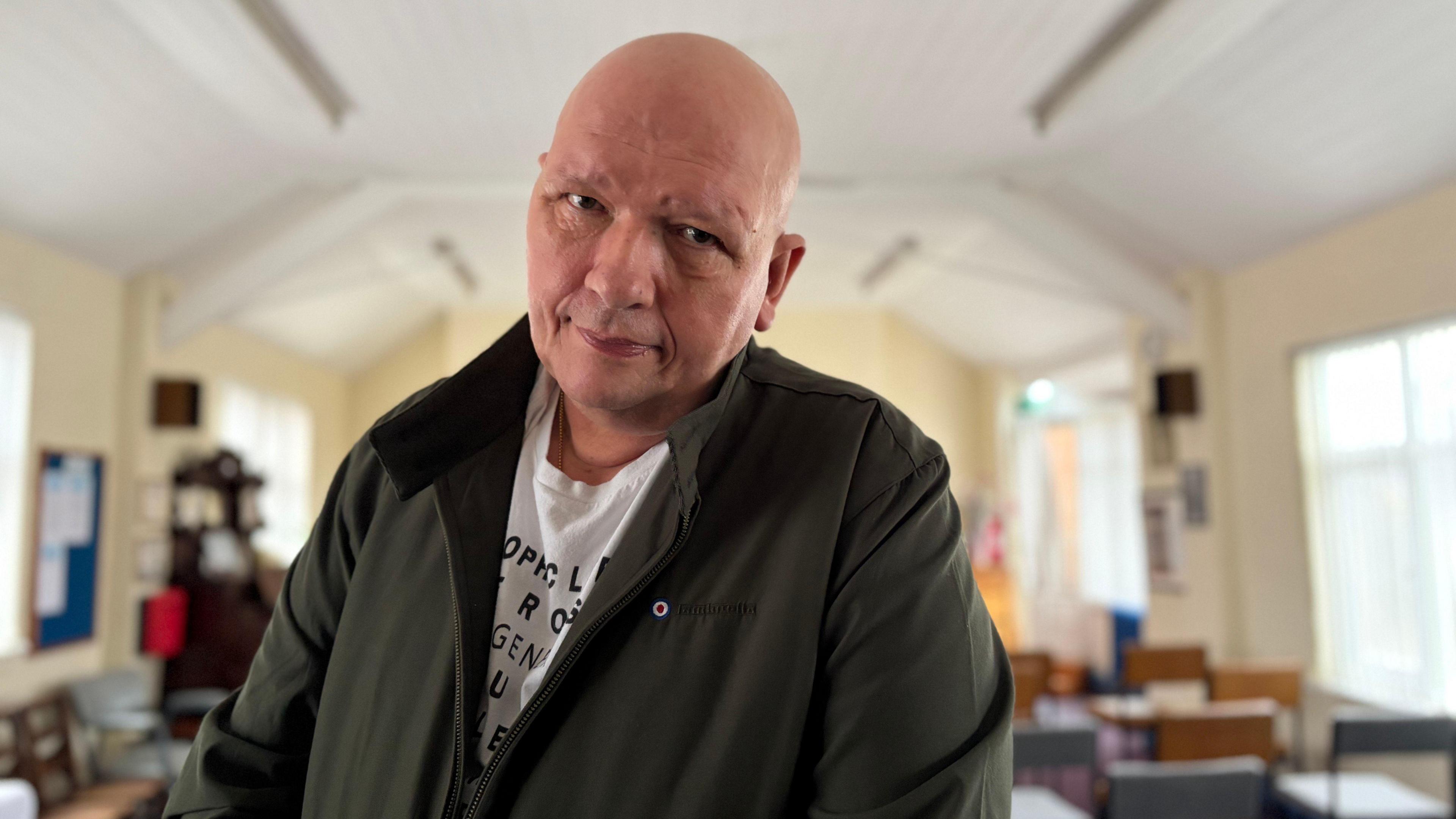 A man wearing a dark green coat stood in a church building