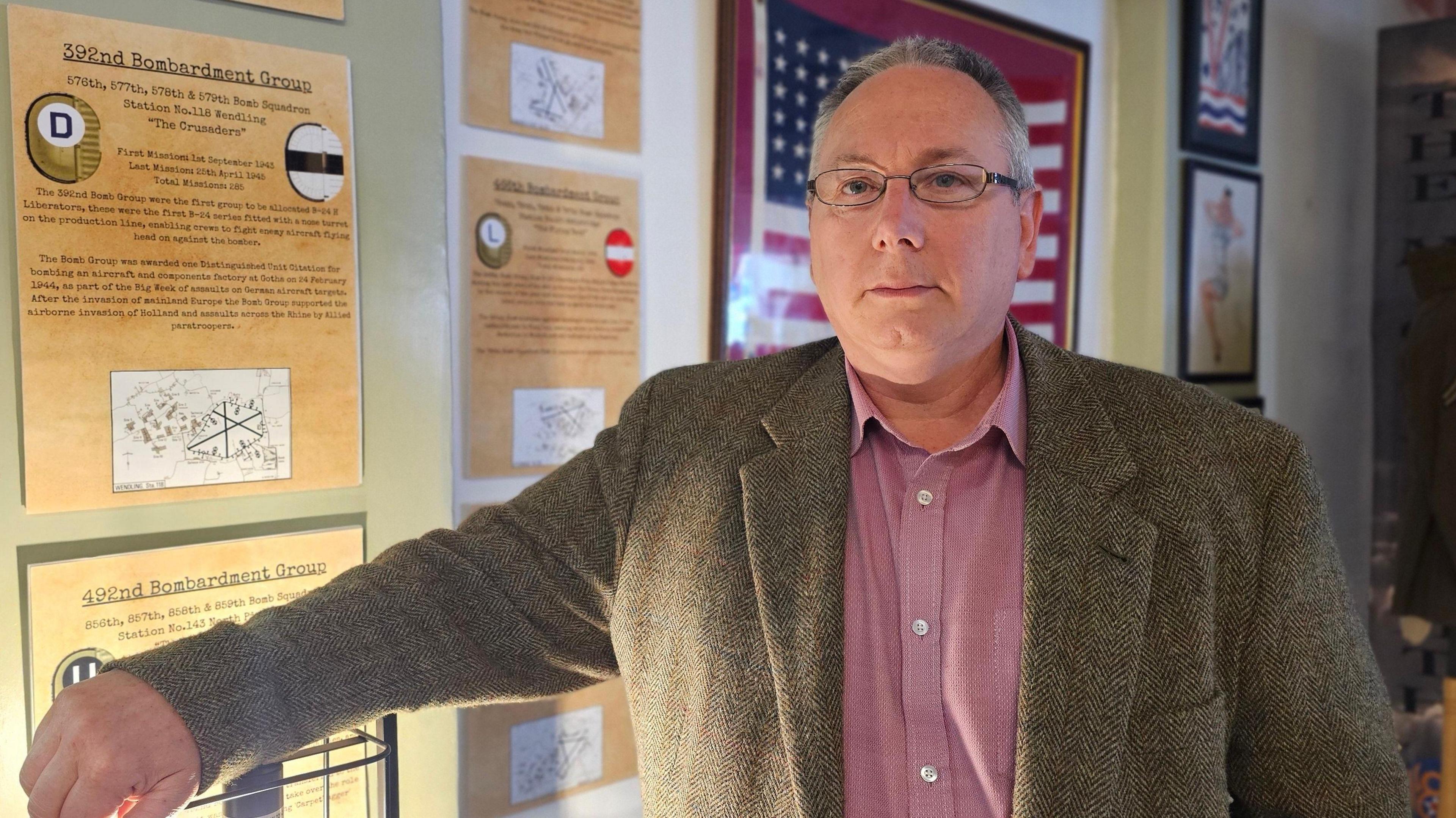 James Clarey standing in front of various information plaques. 