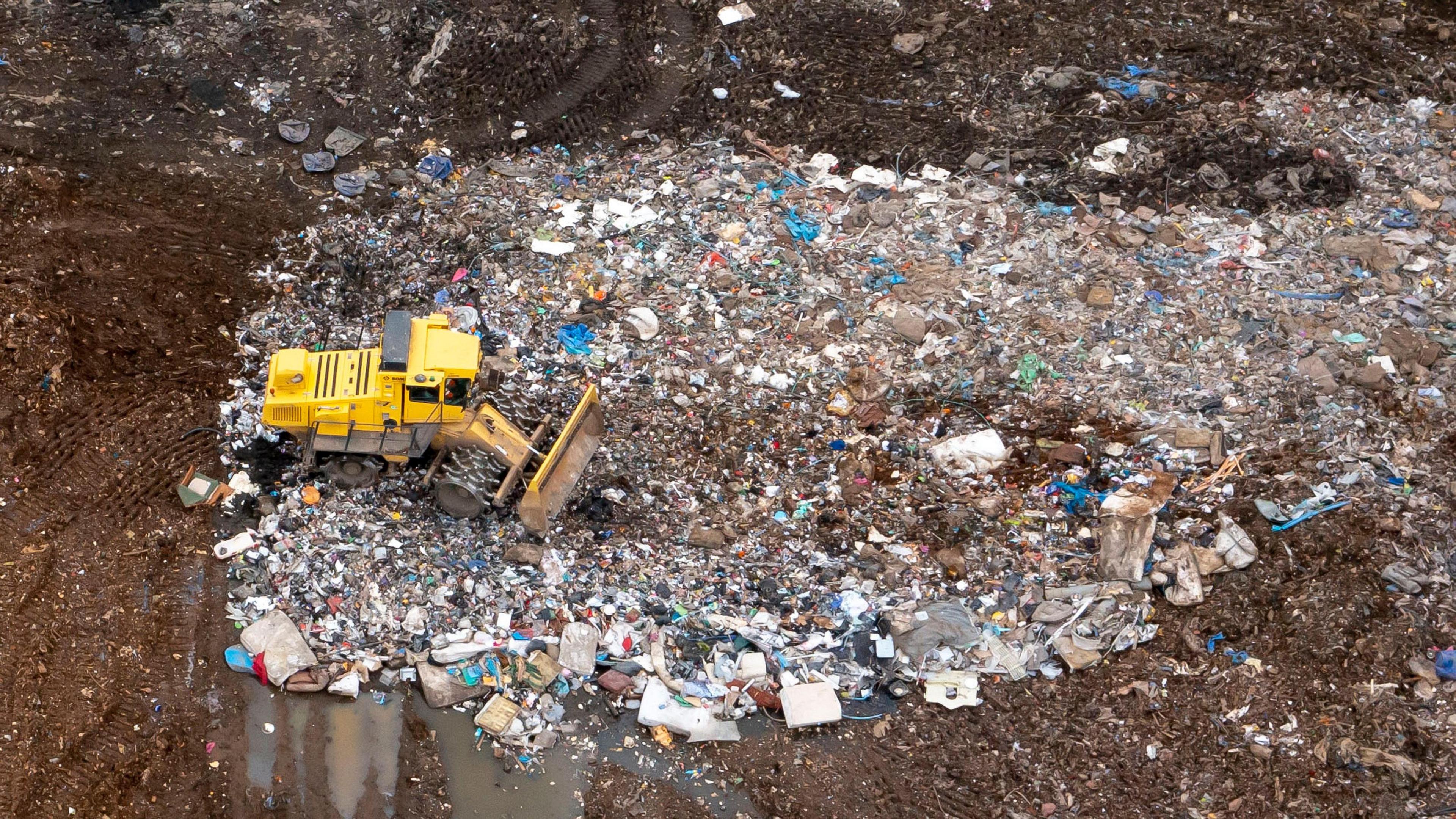 A yellow digger clears waste at a landfill site outside Newport, South Wales.