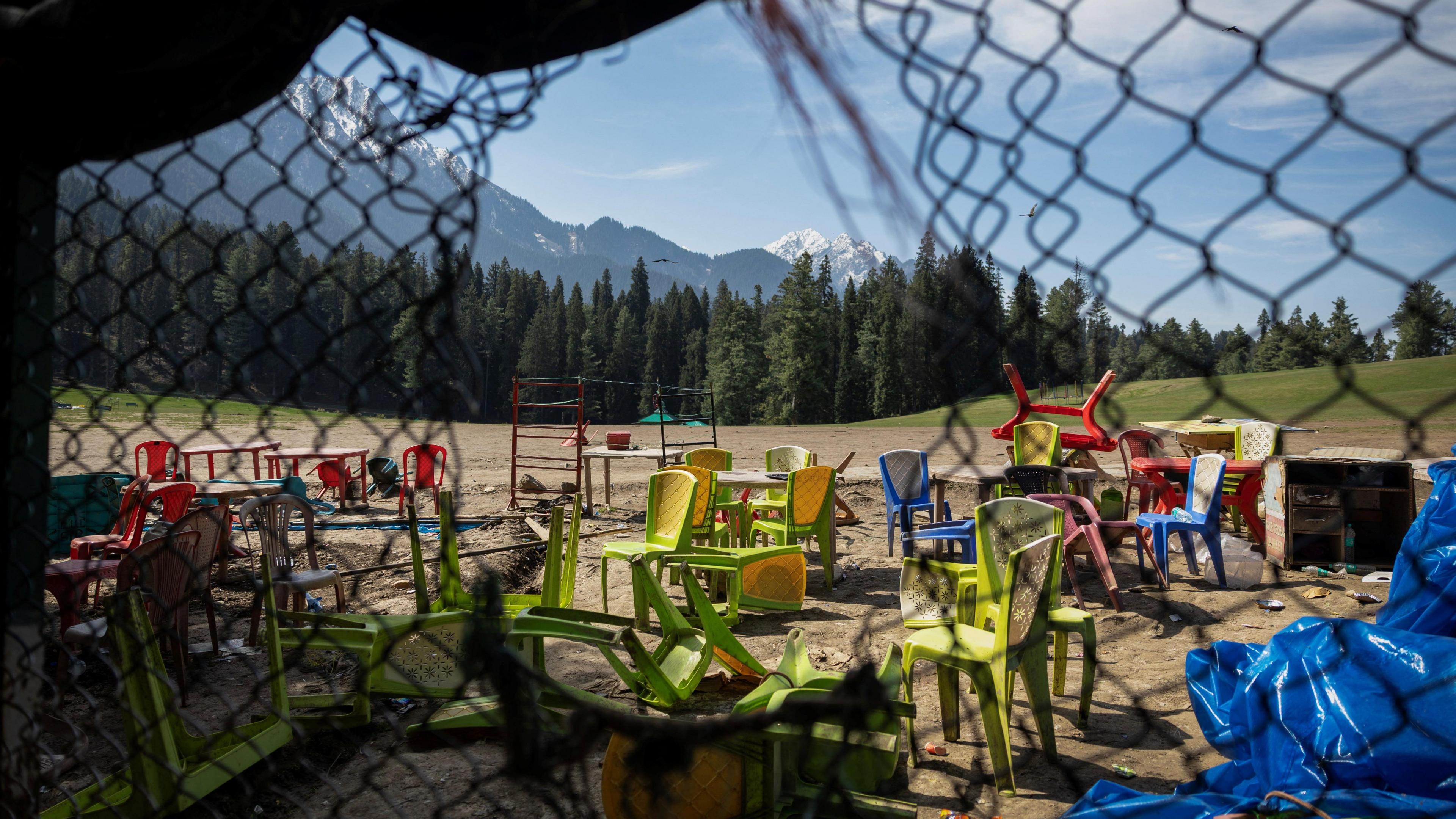 The photograph shows chairs and tables scattered at the site of a suspected militant attack on tourists in Baisaran near Pahalgam in south Kashmir's Anantnag district, April 24, 2025.