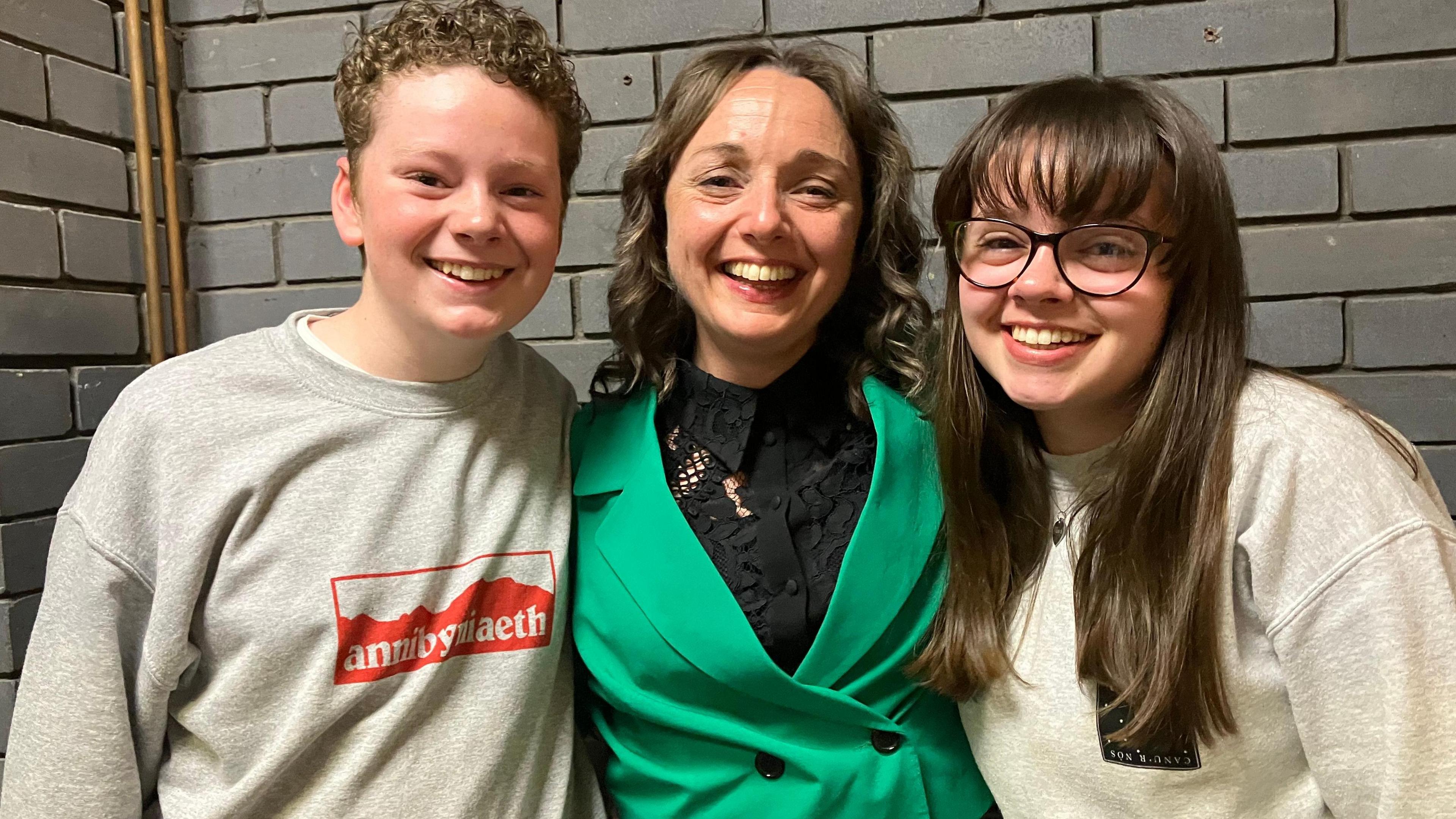 New Ynys Môn MP Llinos Medi smiling at the election count with her arms around her happy children Twm and Elliw