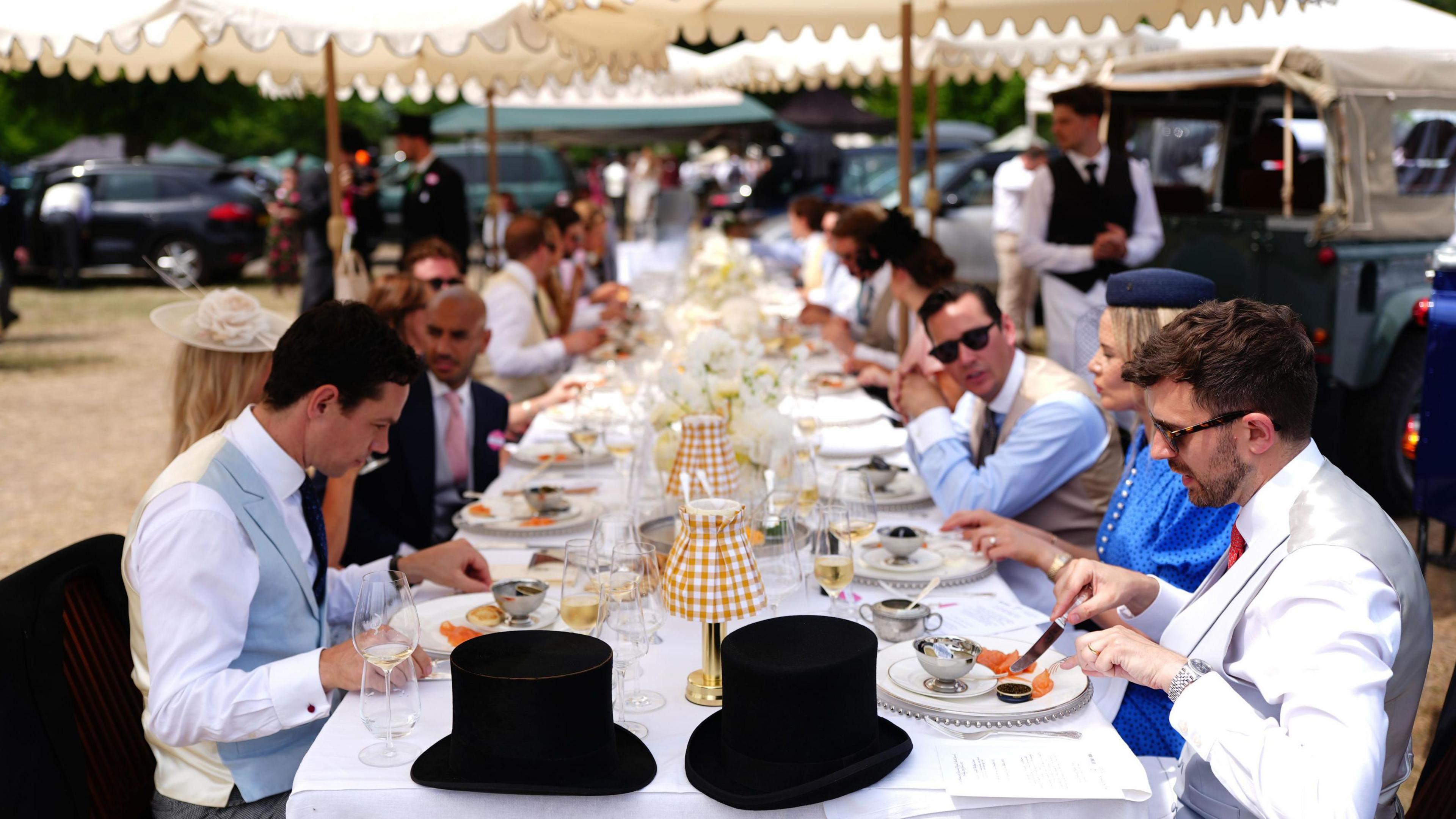 A table with 30 guests eating lunch in the car park on day four of Royal Ascot at Ascot Racecourse.