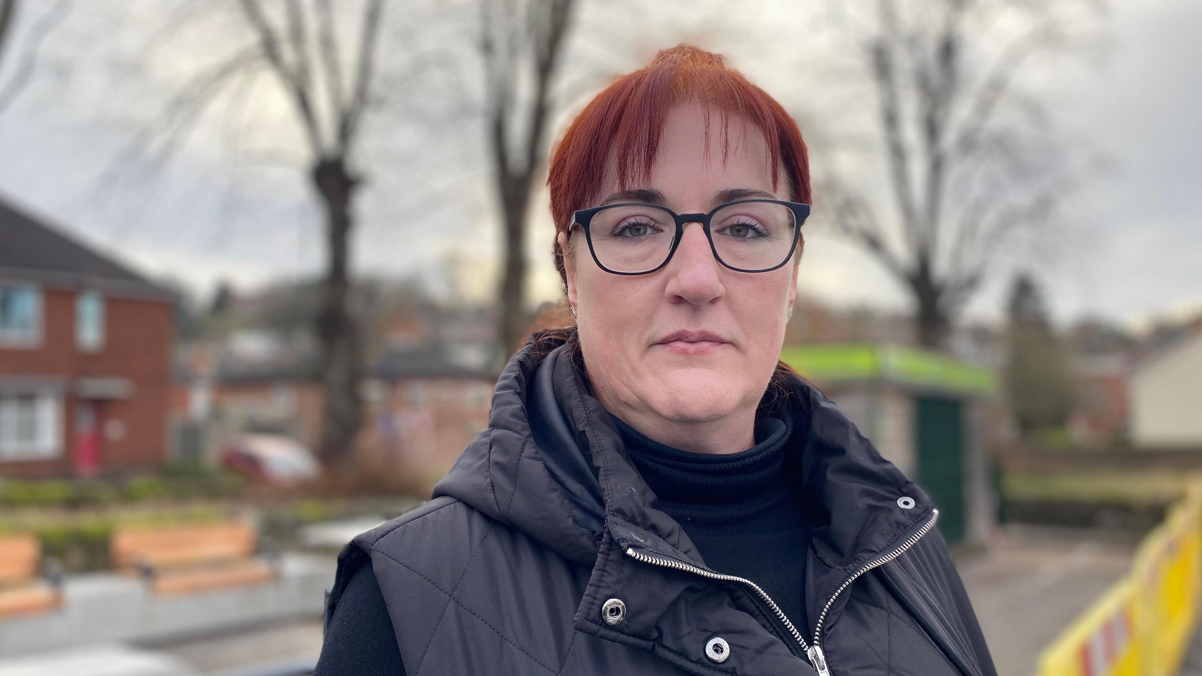 A woman with red hair and glasses