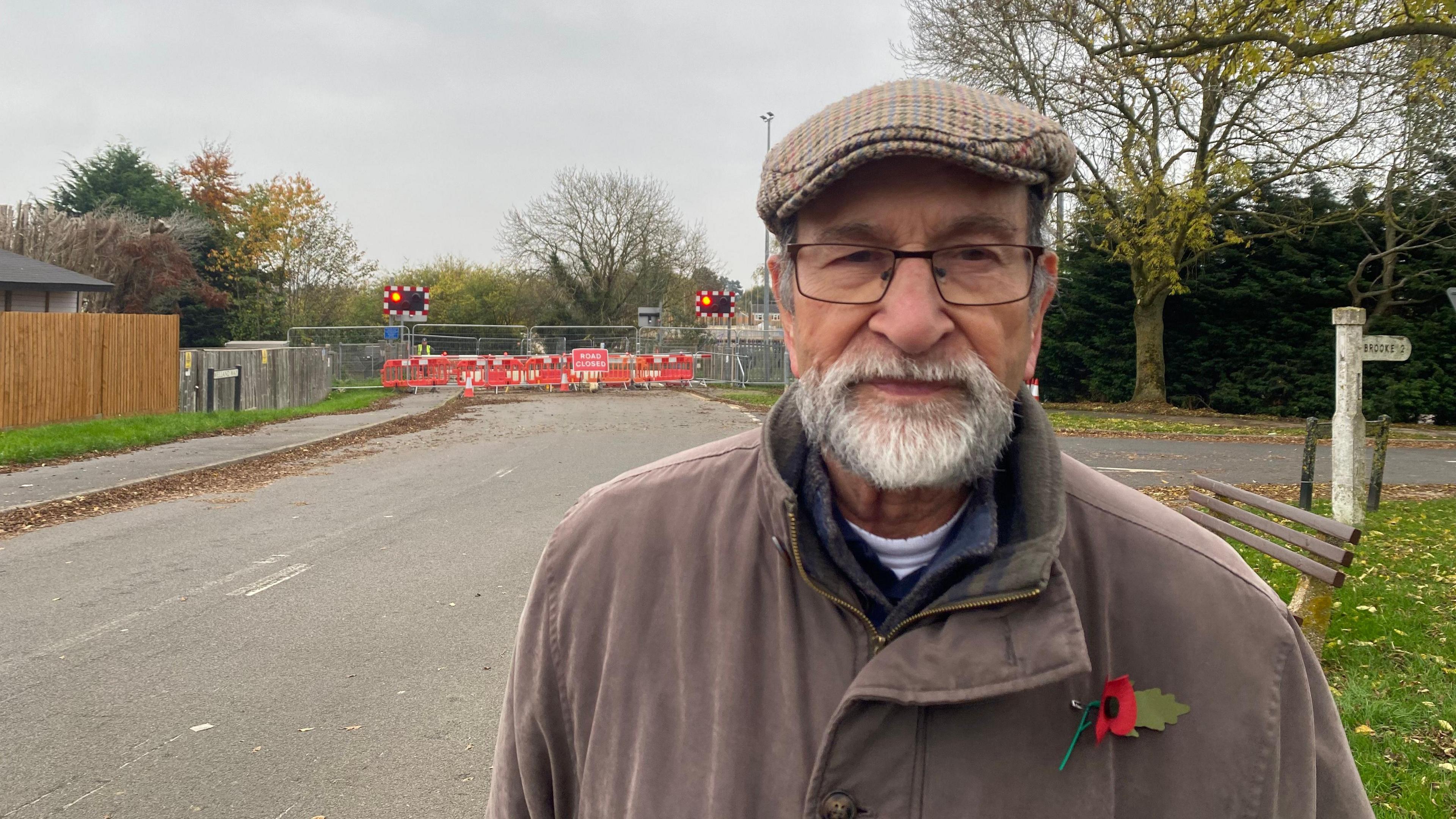 Peter Comber wearing a poppy and flat cap in front of the Brooke Road road works.