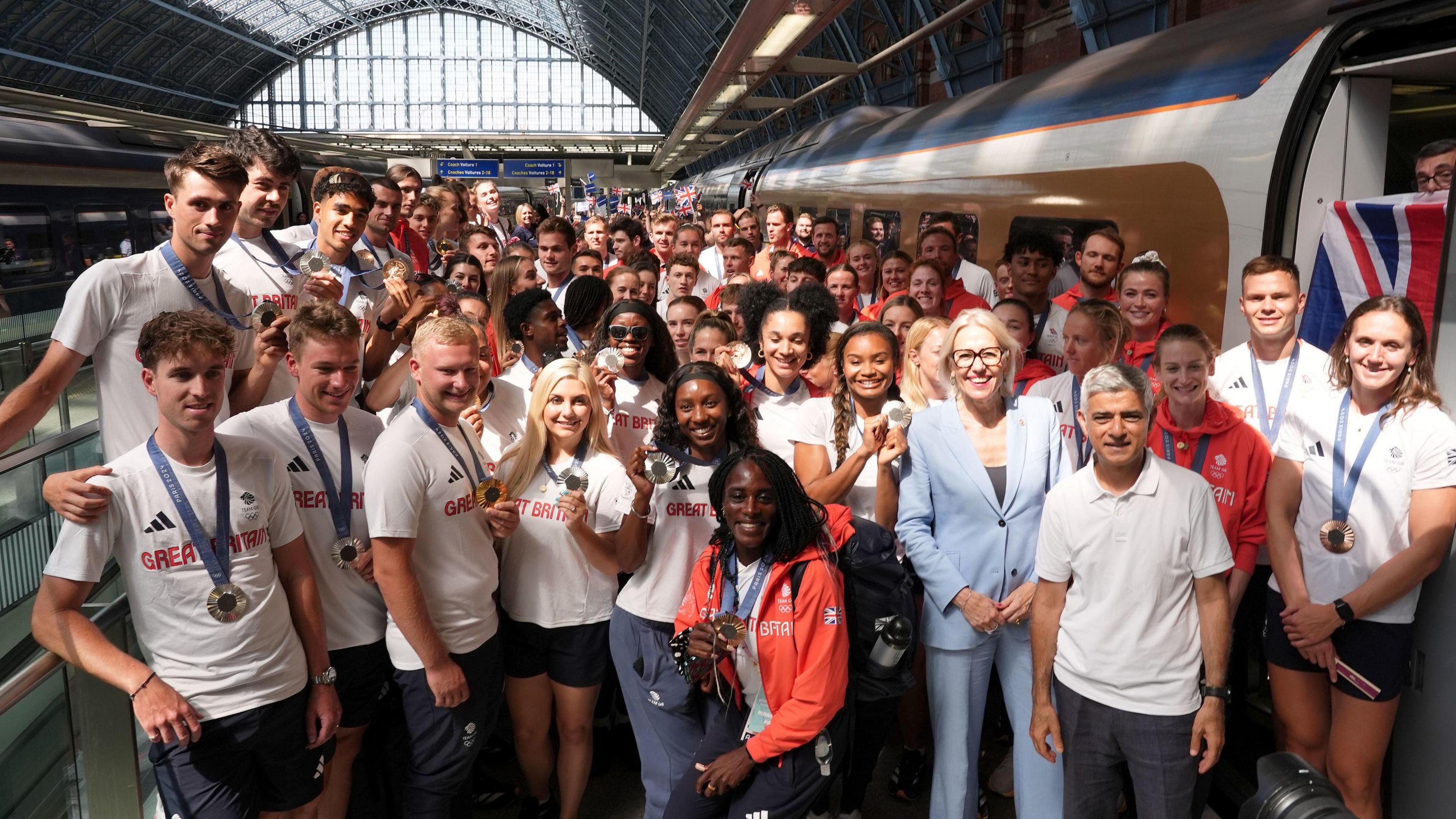 A number of Team GB atheltes pose in front of a Eurostar train