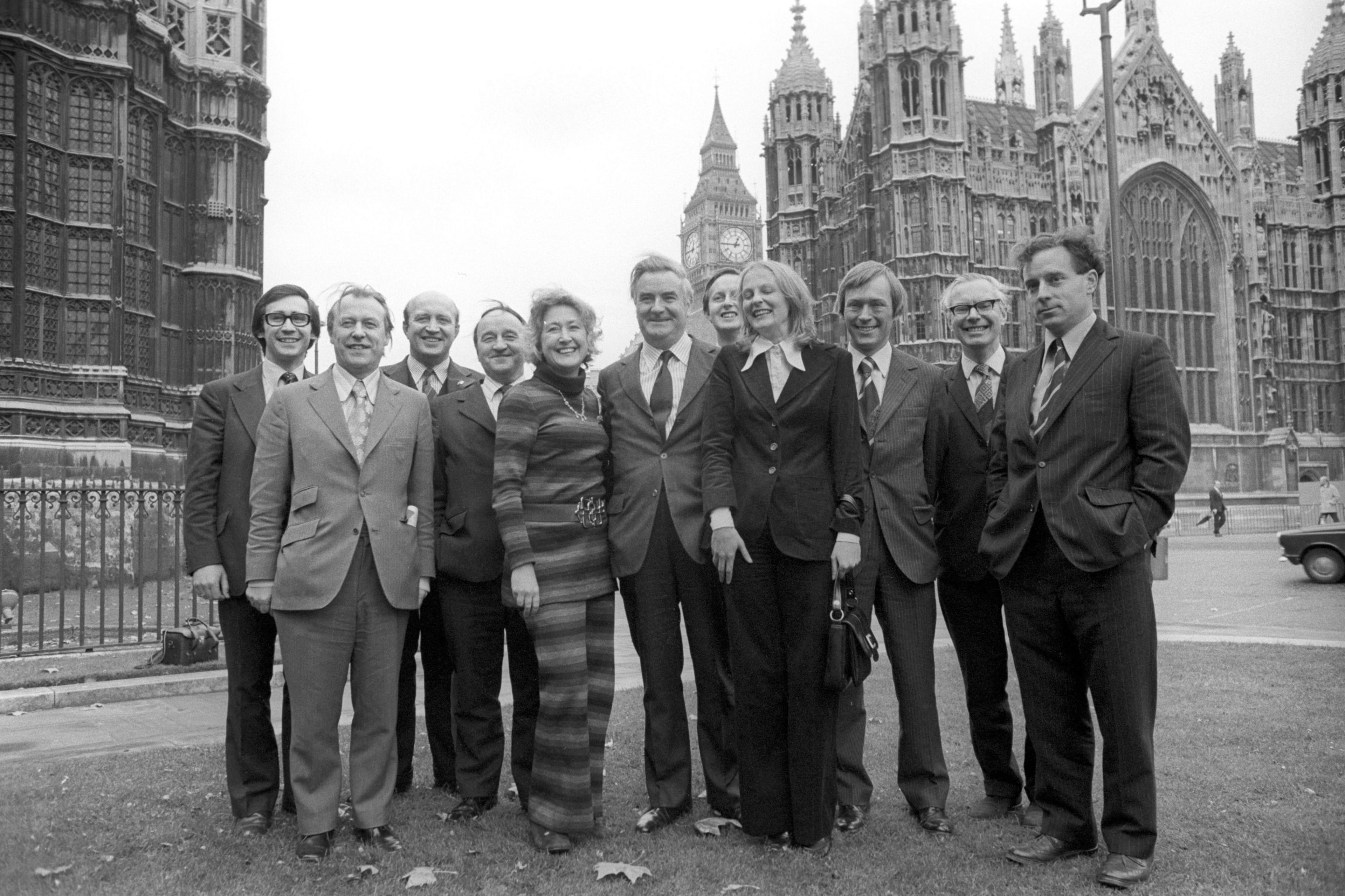 George Reid (third from left) and the SNP "First Eleven" in 1974. A black and white photo of nine men and two women in business dress standing in front of parliament.