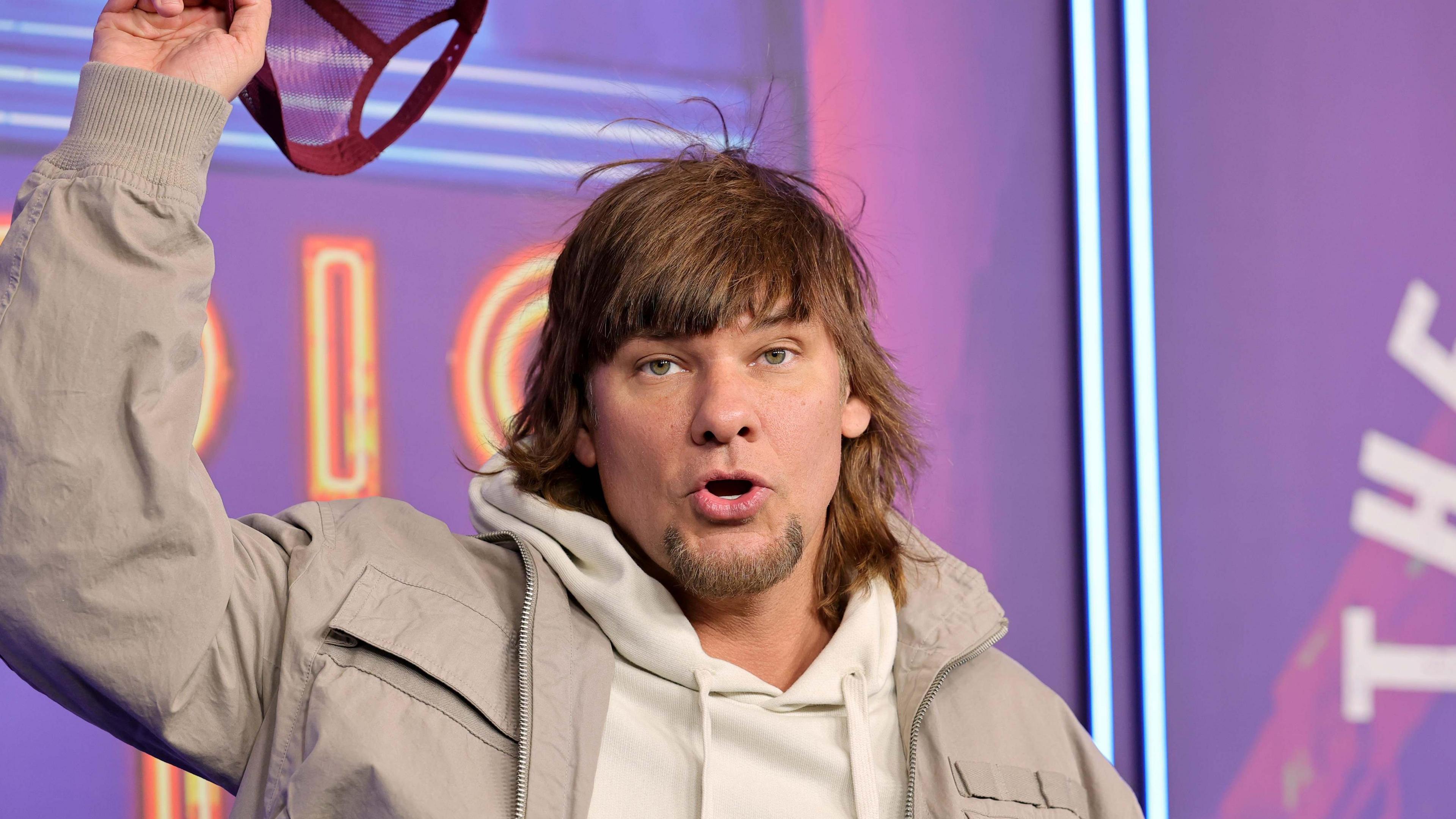 Theo Von wearing a beige jacket and a white hoodie