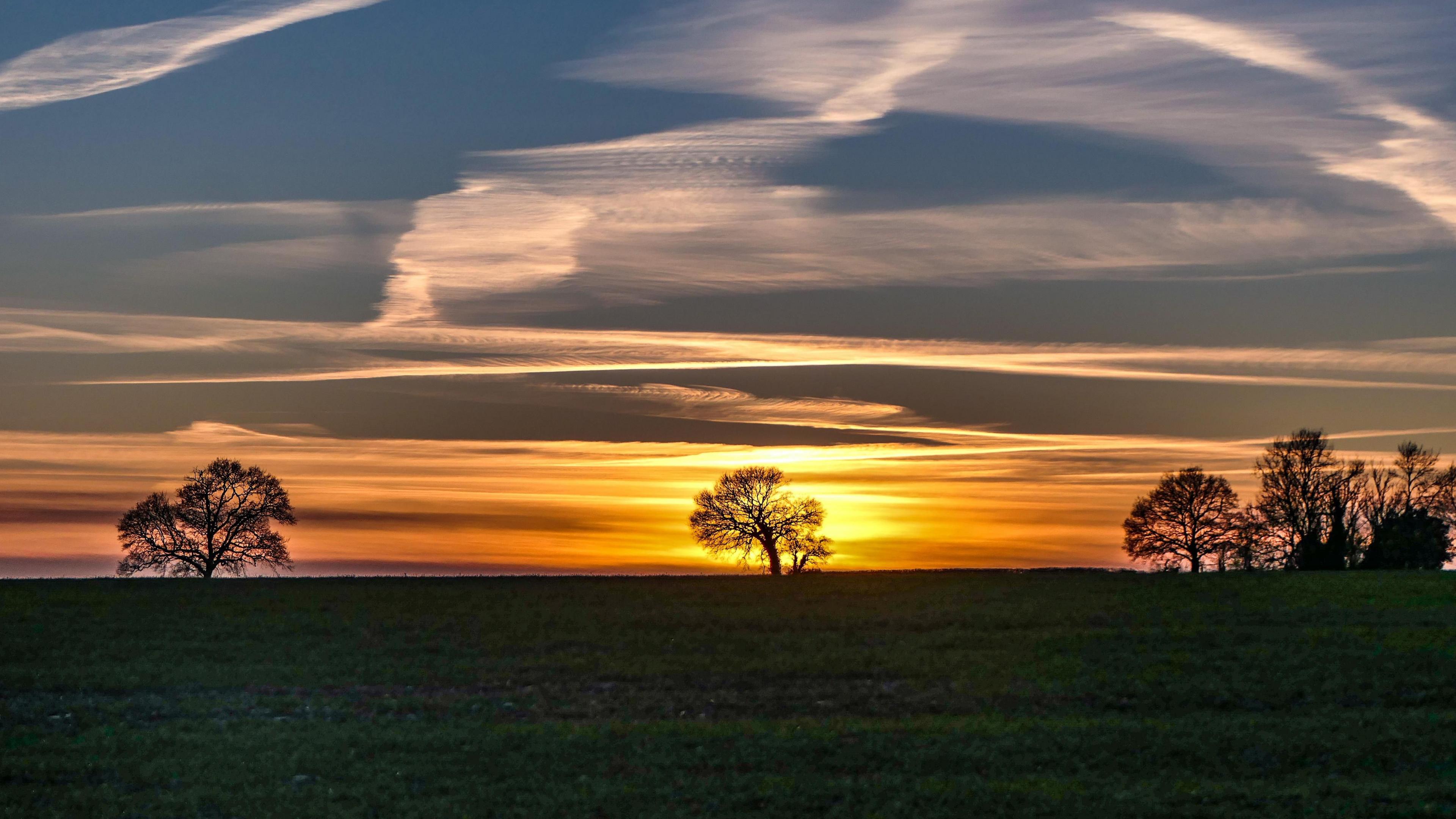 Orange and Blue skies for sunrise over St Mary Bourne in Hampshire, a few distant trees in the background.