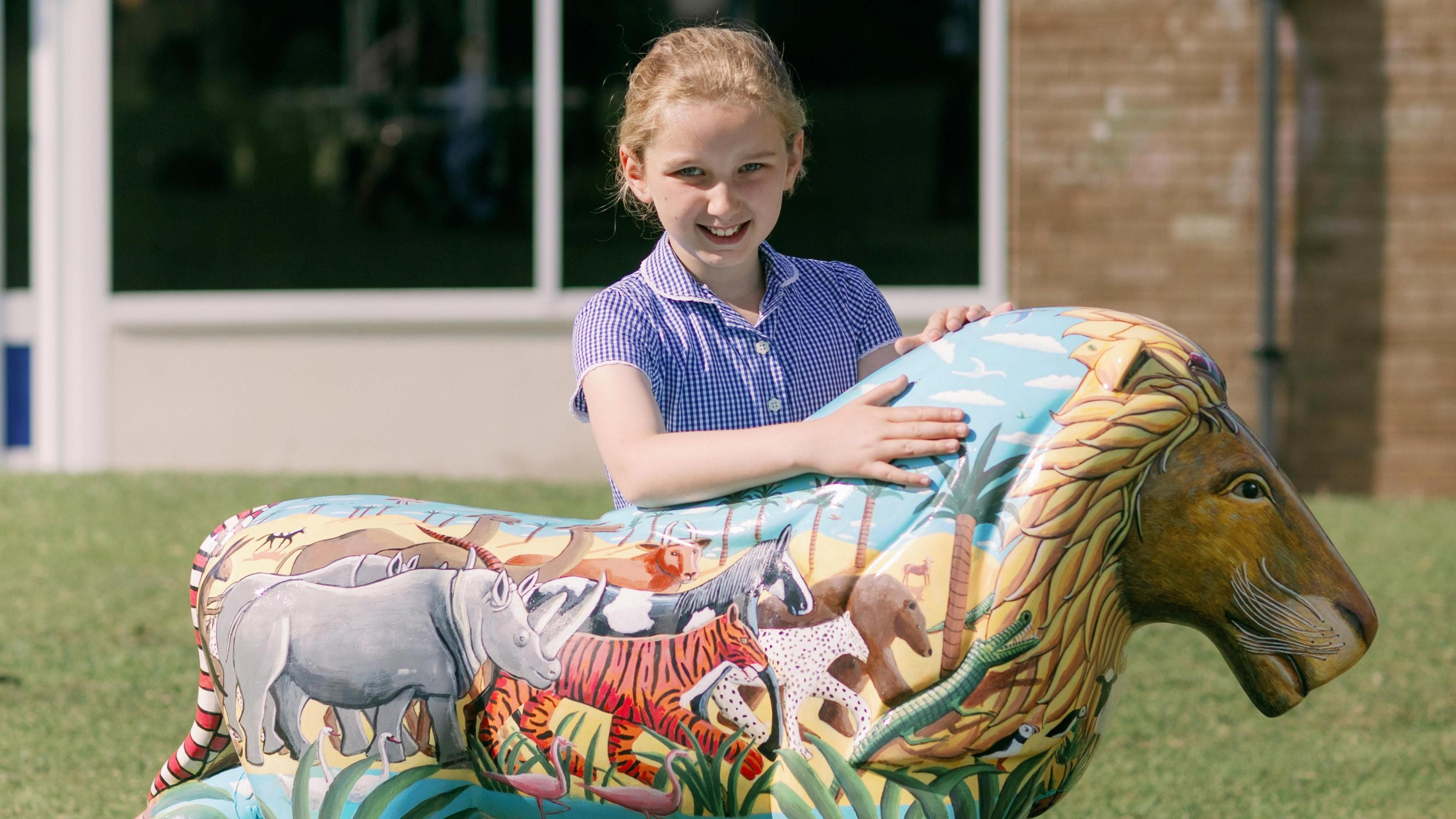 Pupil Sophie pictured with the school's Pride of Gloucestershire lion sculpture - which is painted with a range of other animals, such as rhinos, tigers and a bears