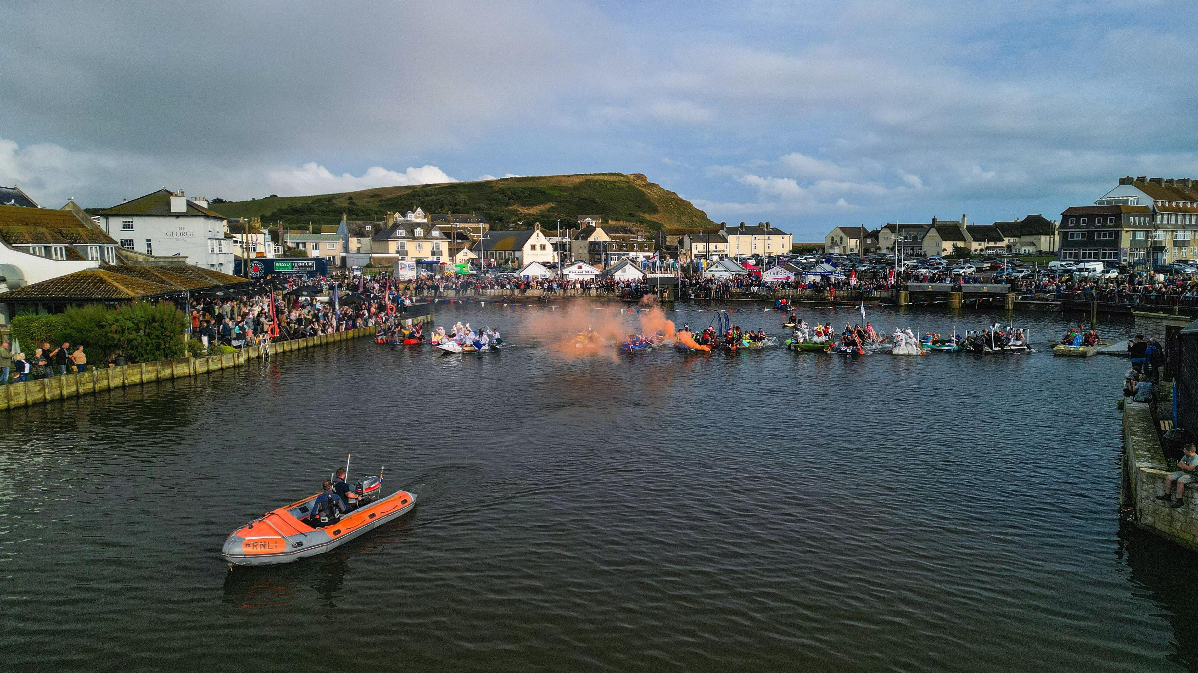 crowds of spectators sat and stood around the edge of the river