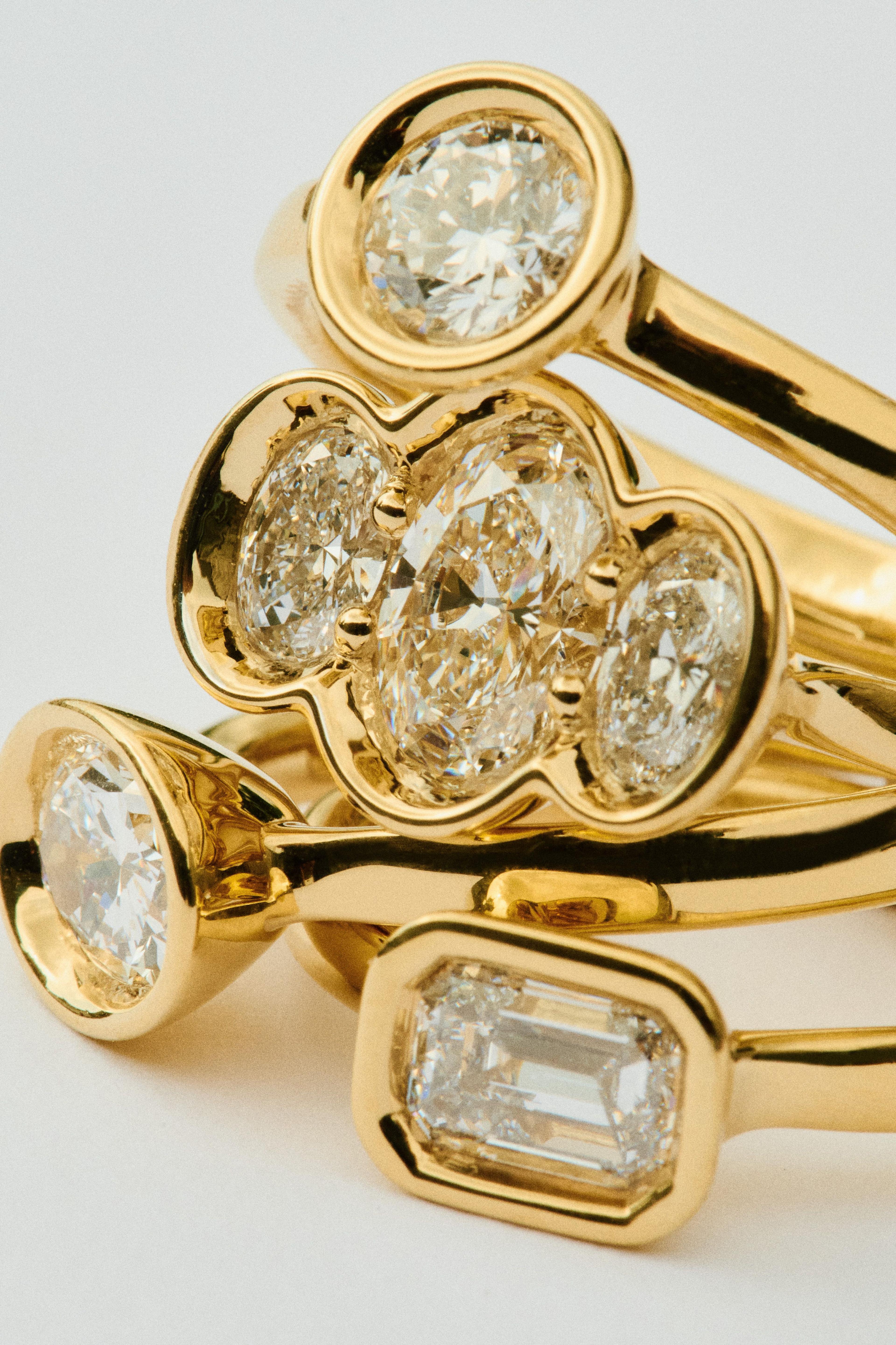 Gold-coloured engagement rings featuring diamonds in different shapes and sizes stacked on top of each other