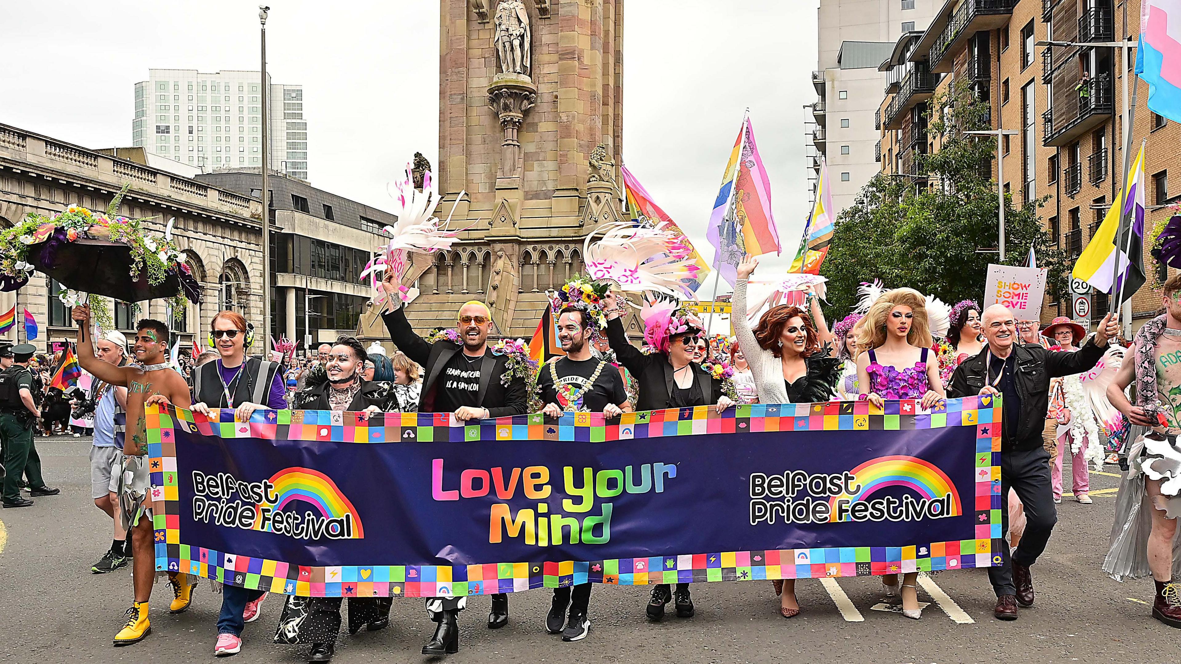 Group of people carrying a banner that reads "Belfast Pride Festival. Love your Mind".