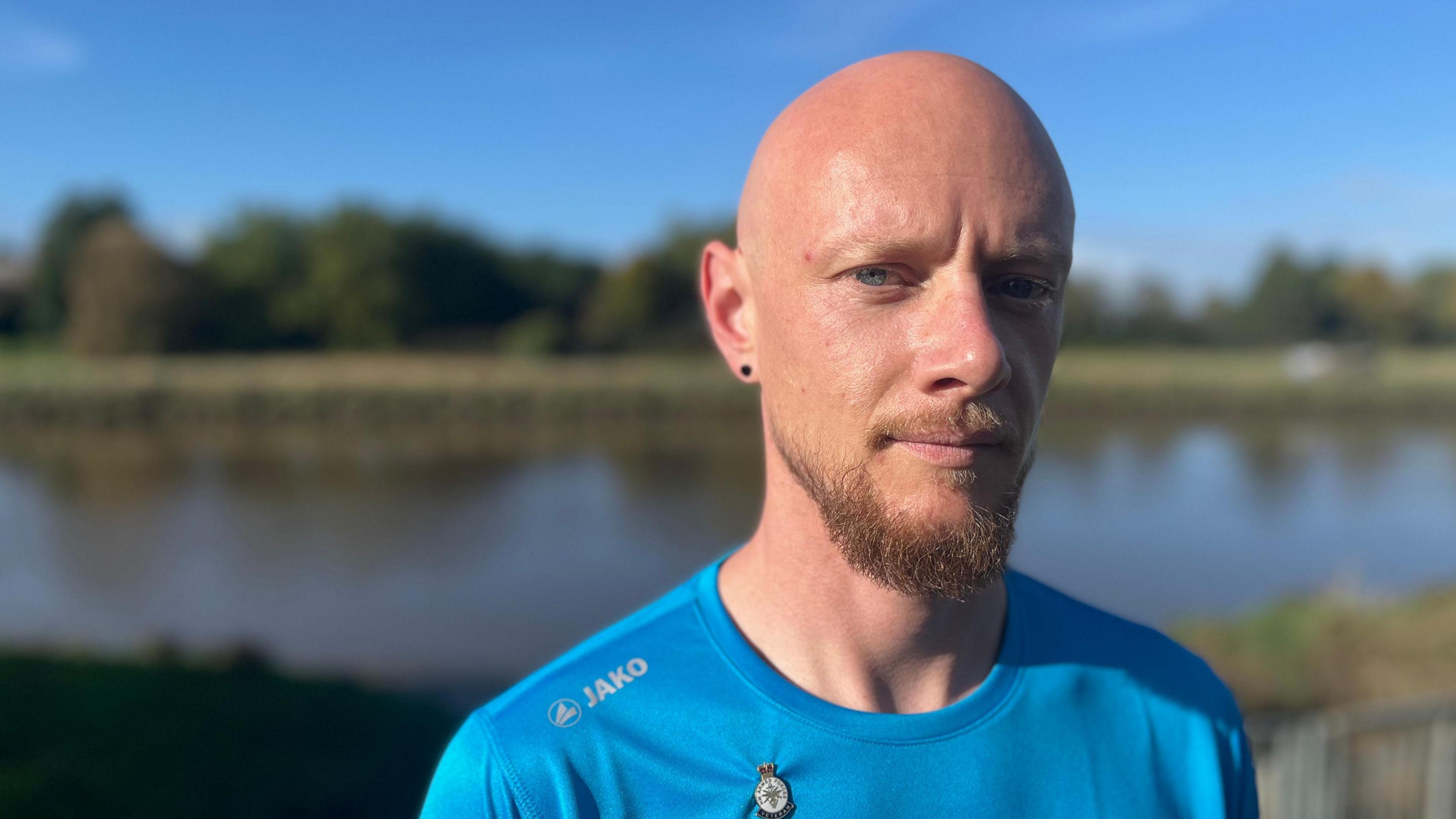 Myles Weston, wearing a blue T-shirt, againsta  blurred background showing the river.