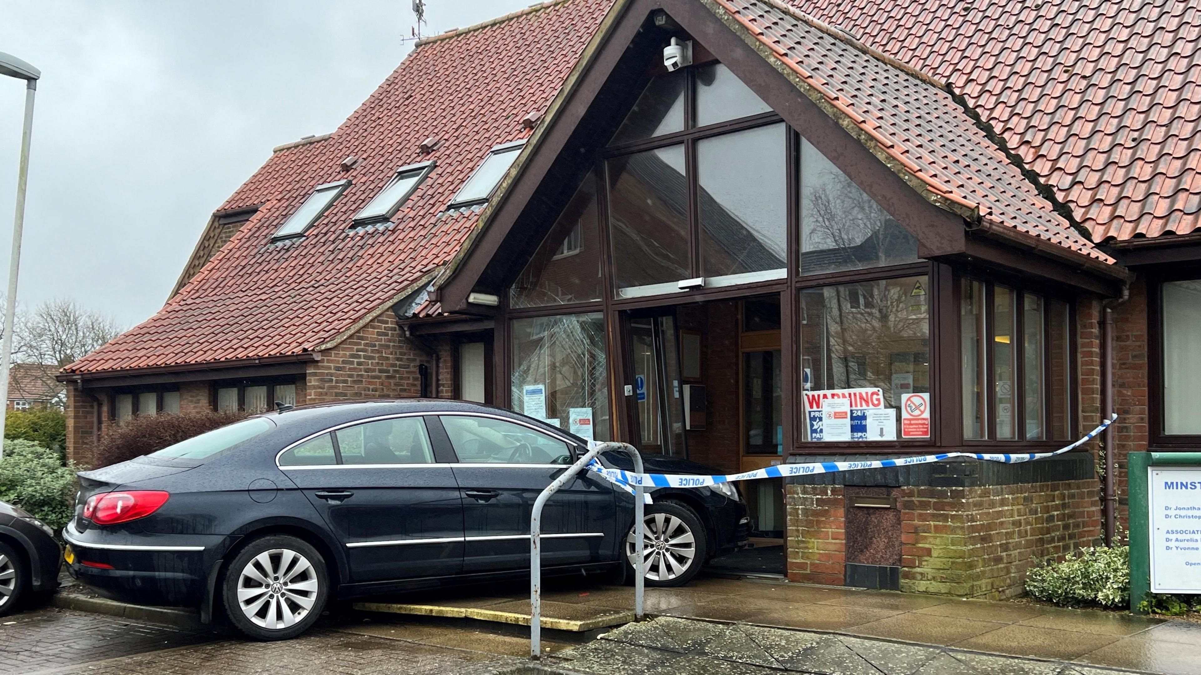 A dark blue car in the front of a Lincoln GP surgery