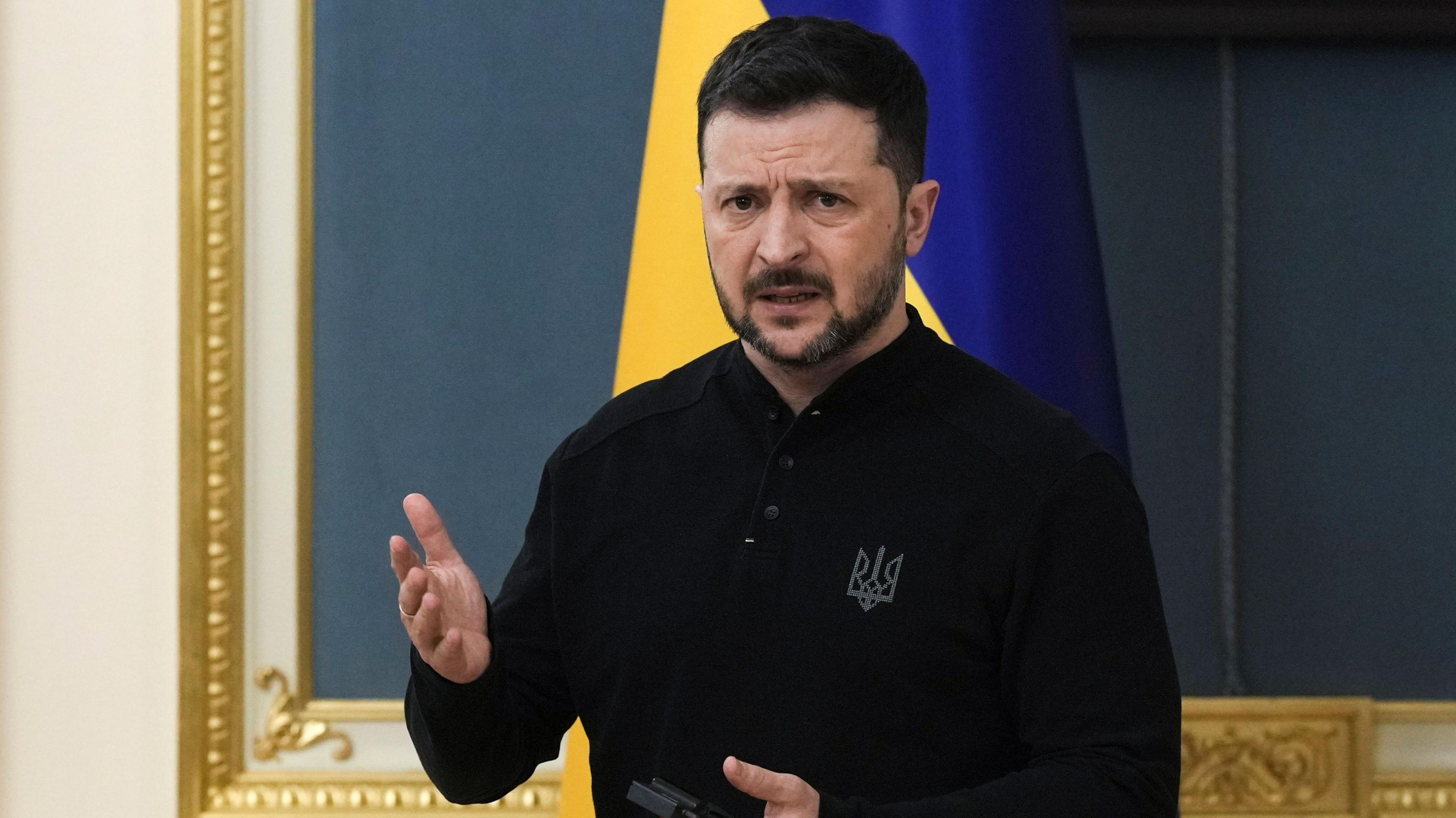 Ukrainian President Volodymyr Zelensky addresses a press conference with a Ukrainian flag behind him