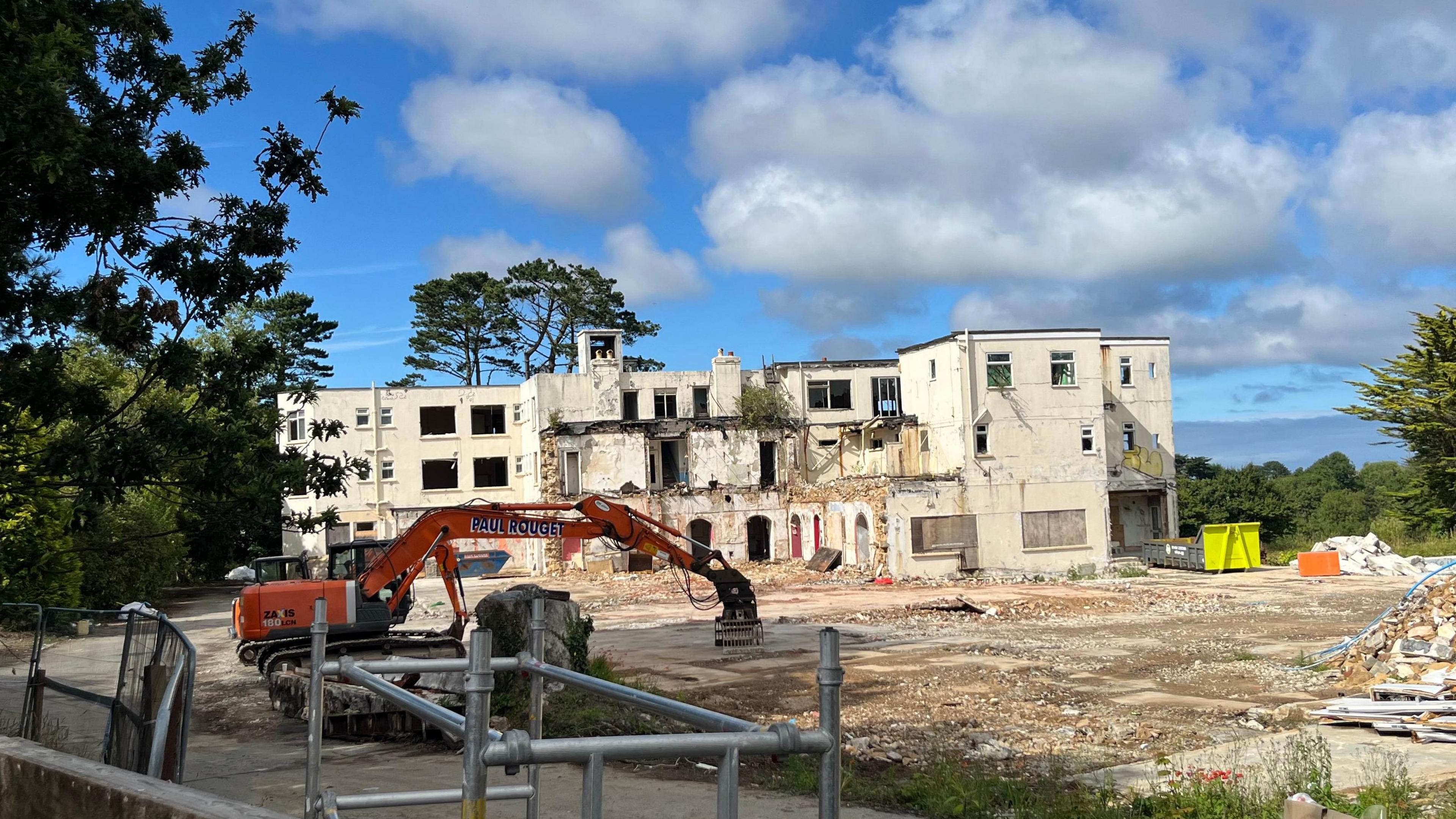 The St Martin's Hotel, a big yellow building that has been partially demolished. In front of it is an orange digger with the words Bob Froome on it.