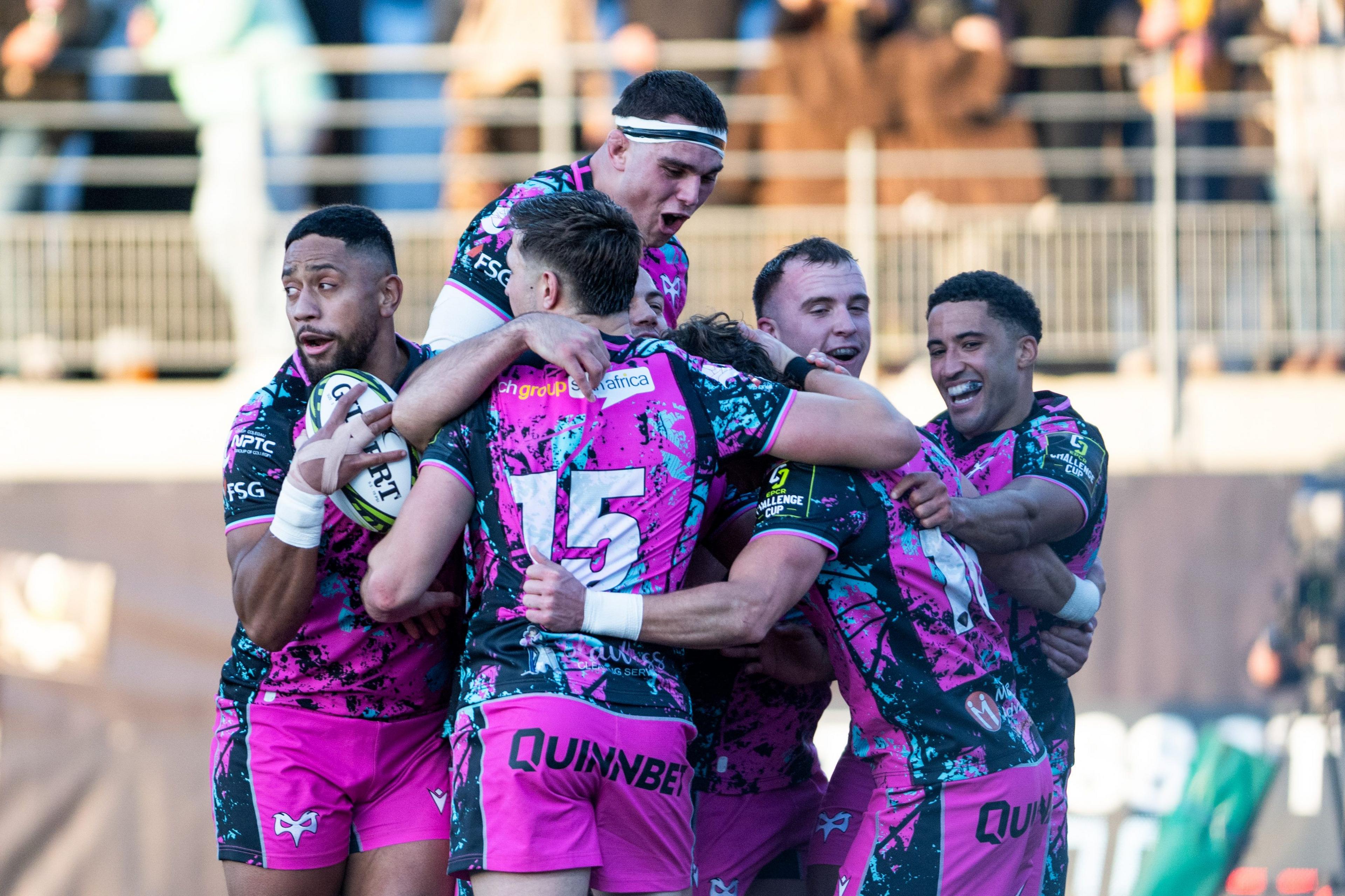 Six Ospreys players in a huddle celebrating scoring a try in their win at Montauban in the Challenge Cup
