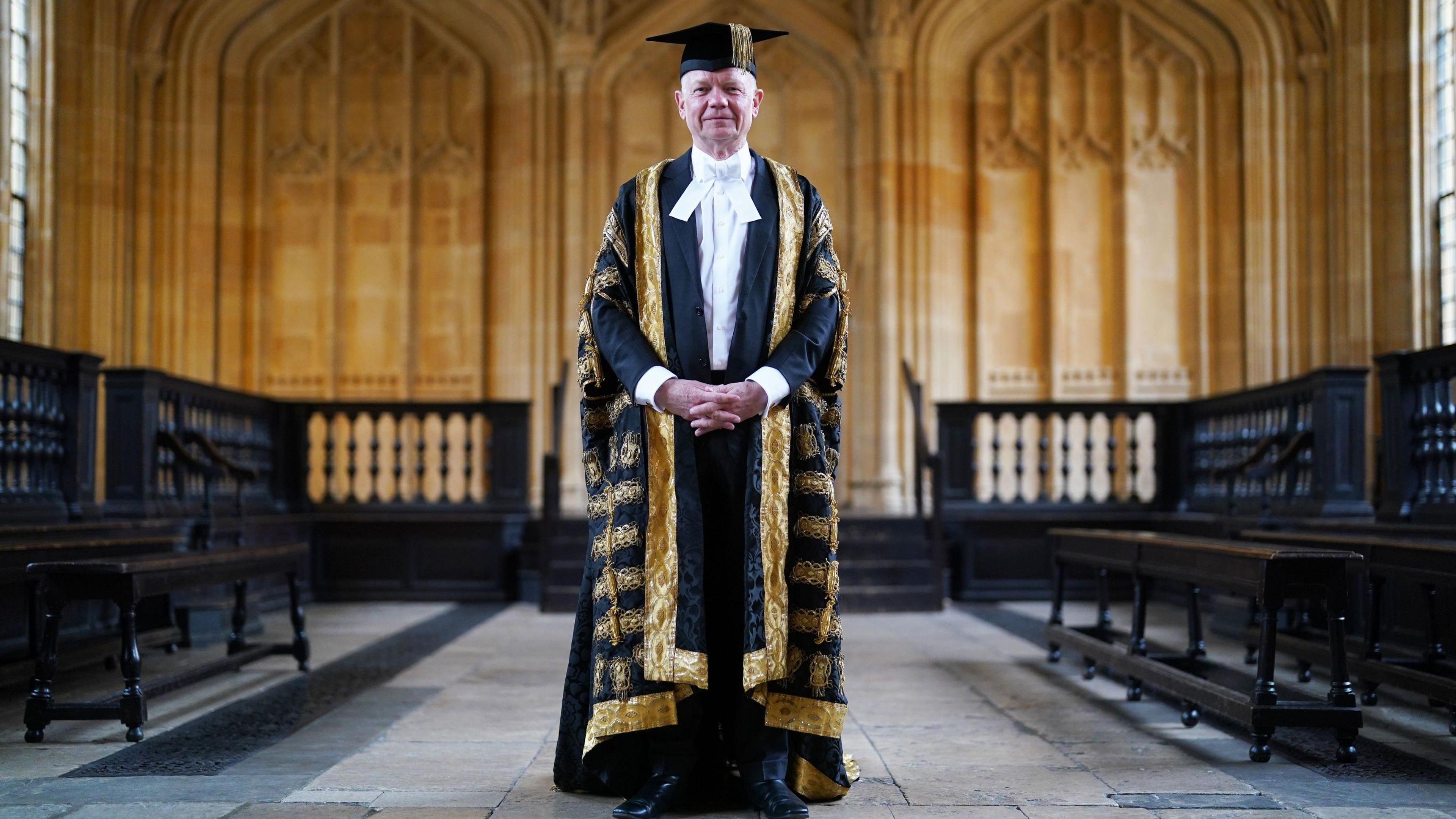 Lord William Hague dressed in a robe and cap for his inauguration as the Chancellor of Oxford University stands looking at the camera with his hands joined in front of him at Sheldonian Theatre in Oxford.