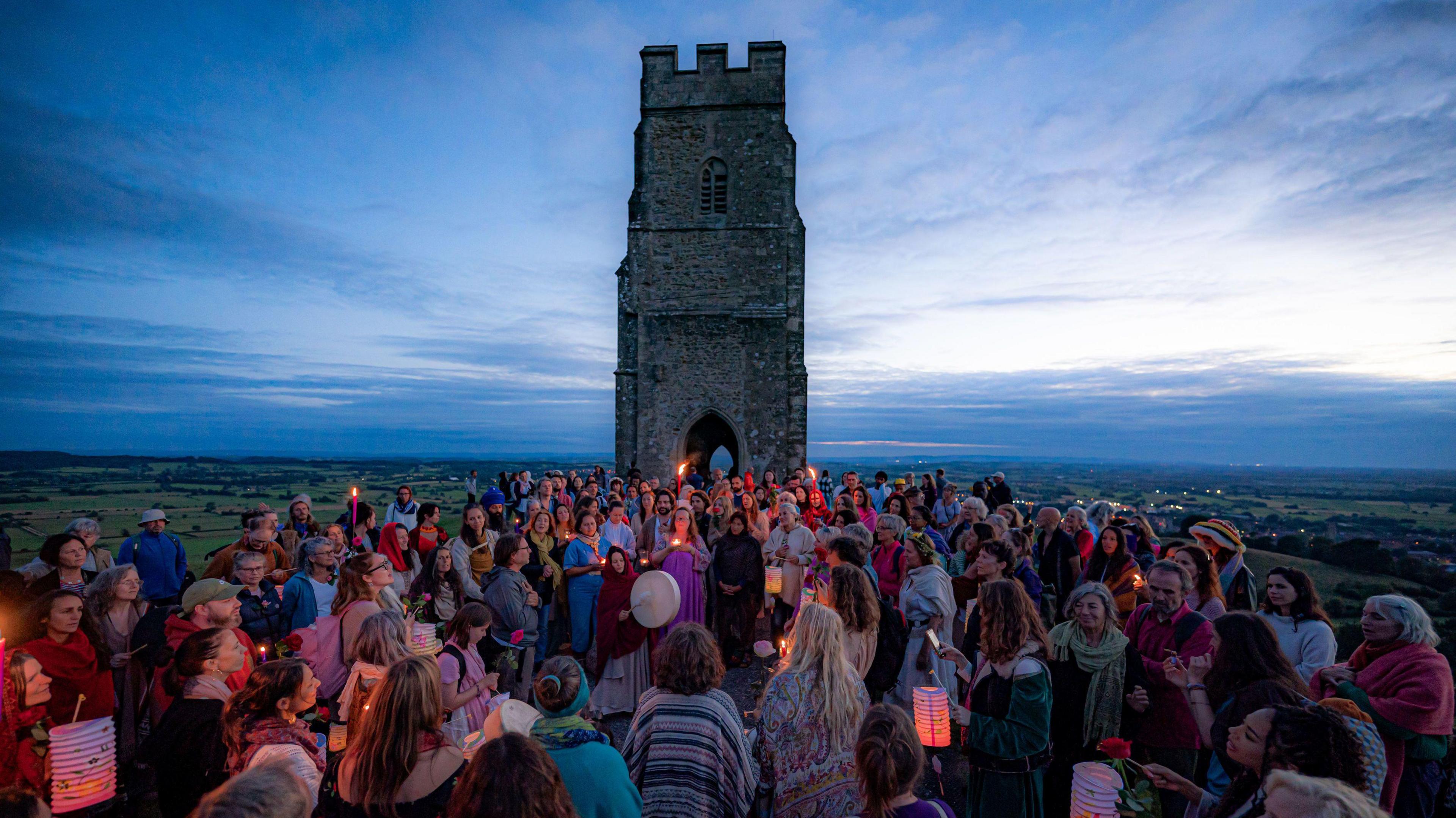 People gathering around Glastonbury Tor as the sun rises