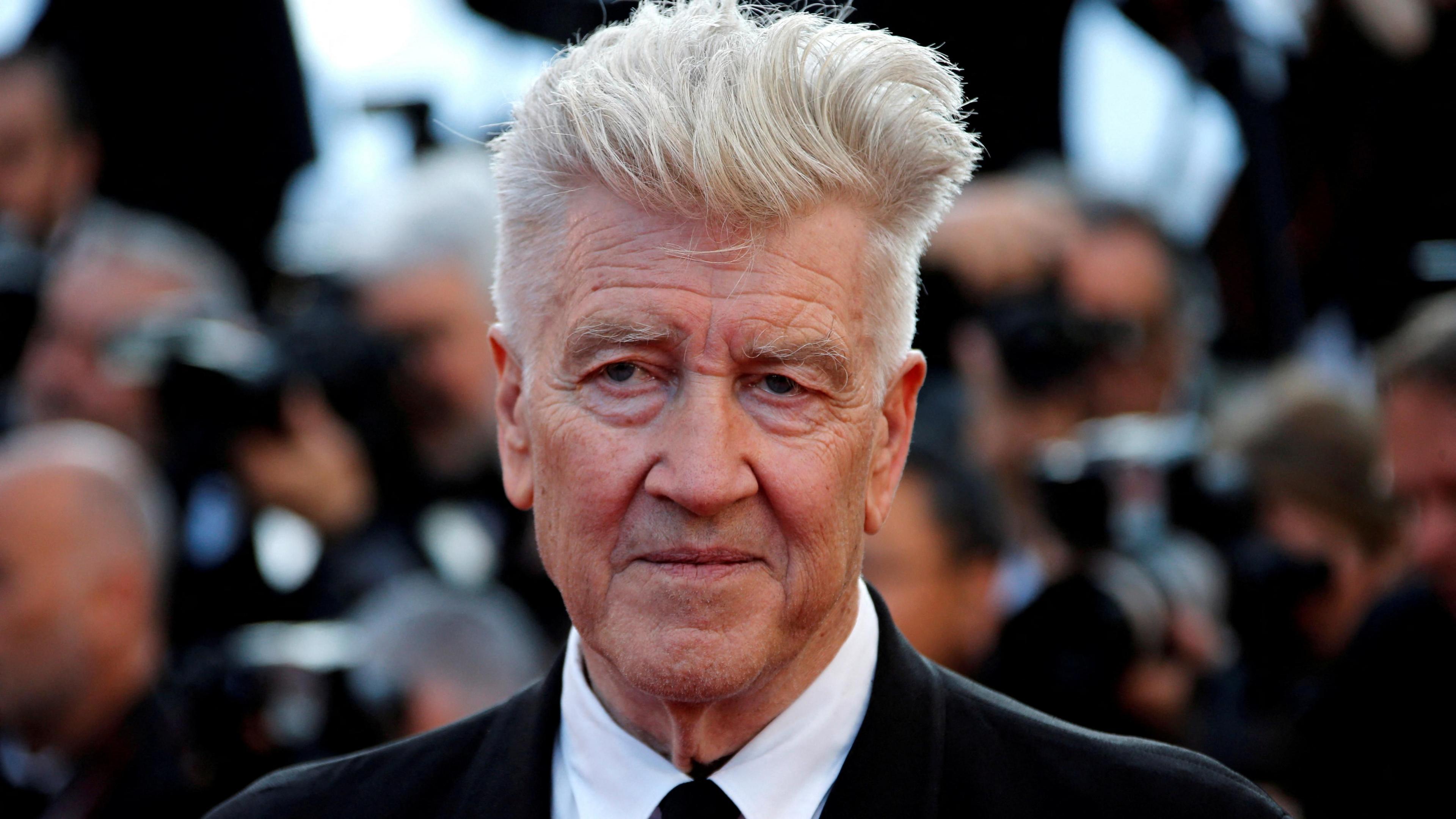 David Lynch wearing a black suit and tie