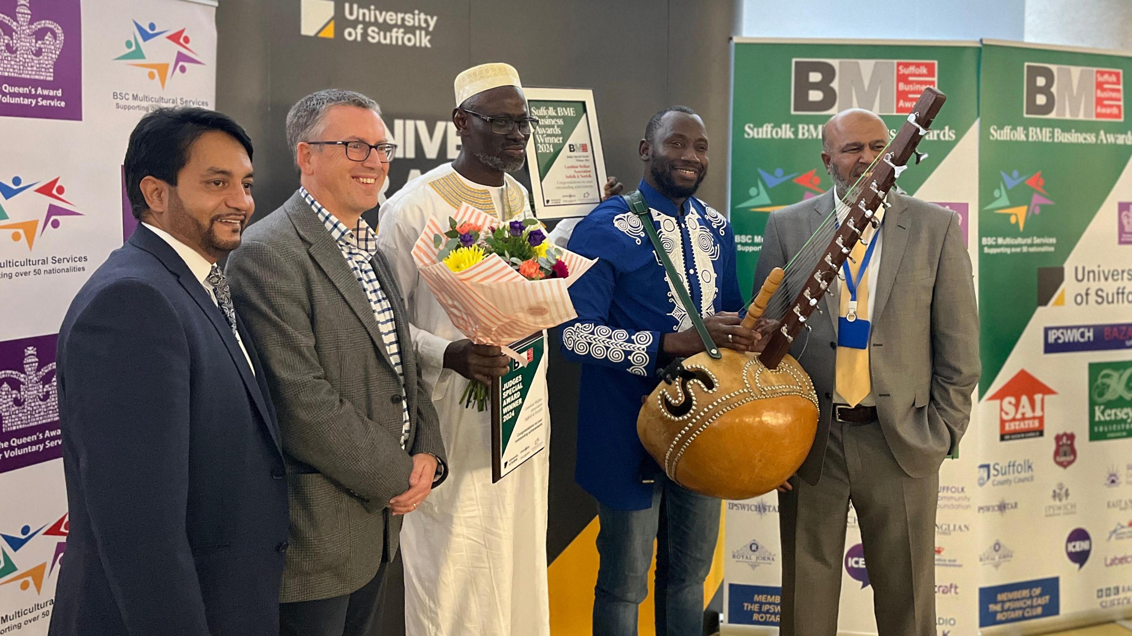 Sefo Kanuteh holding a large kora, a traditional African 12 stringed instrument.