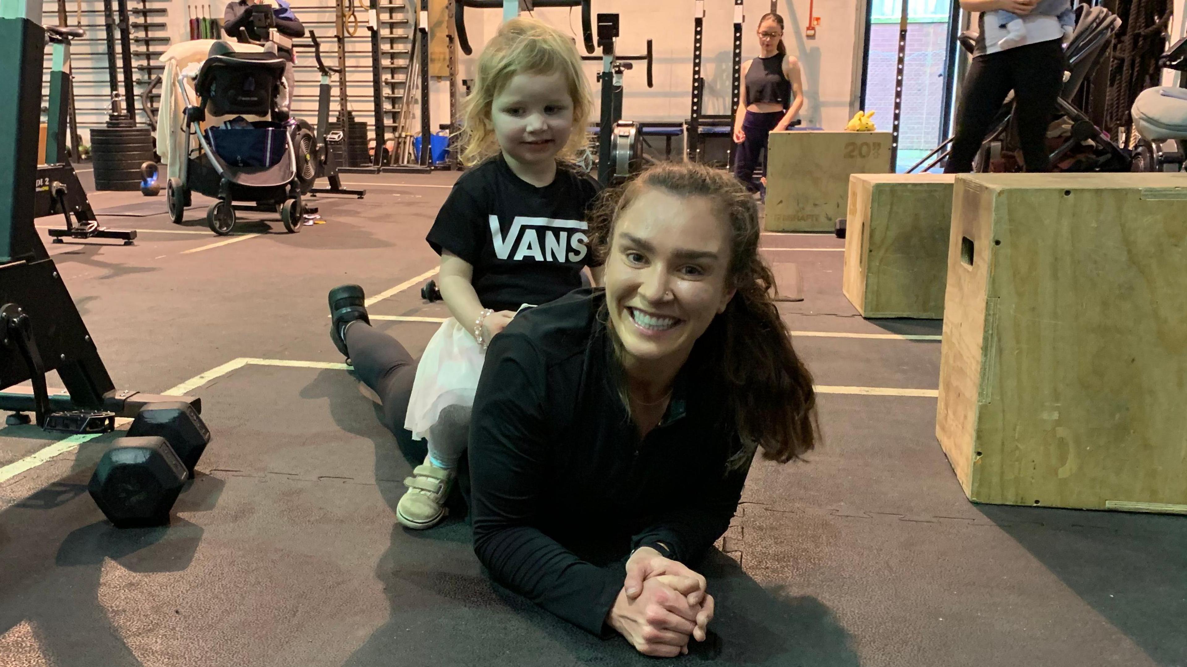 Emma Clayton a regular at the classes in Llanishen exercises with her daughter, Olive, sat on her back.