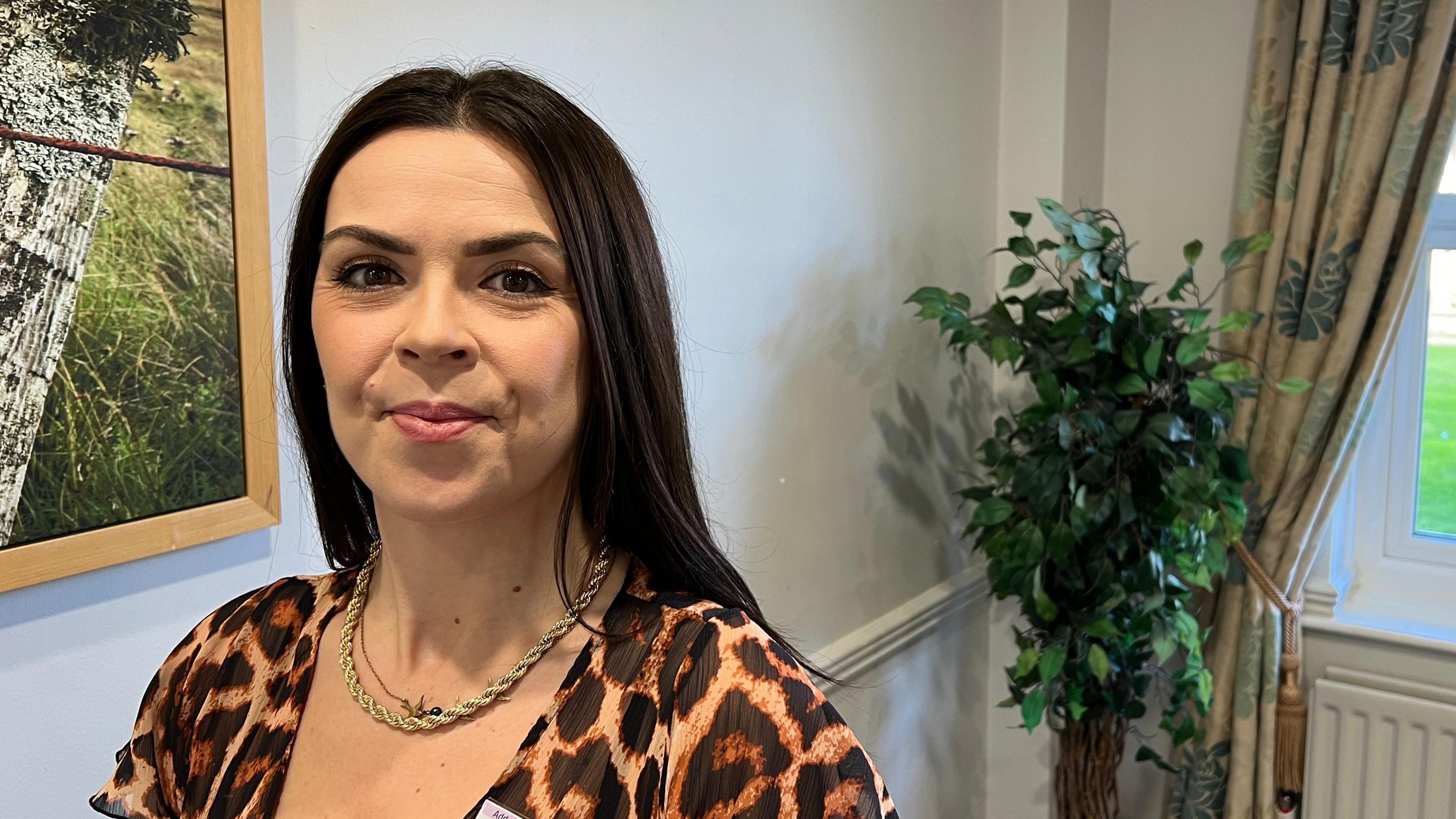 Laura Pulleyn, who shared her experience of domestic violence at a summit organised to address the issue. She is looking towards the right of the camera. She has black hair and is wearing a leopard-print dress and a gold chain.