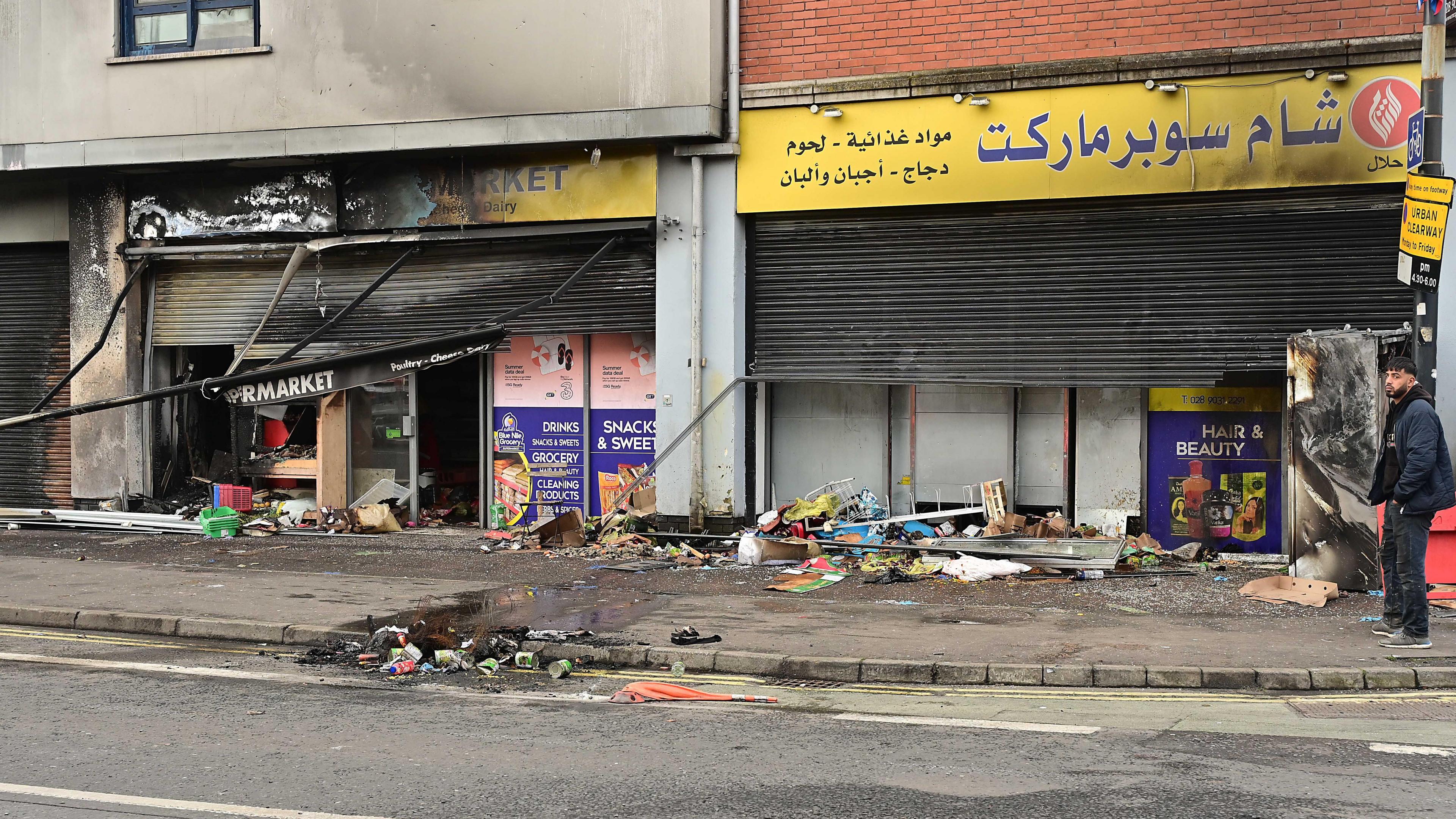 Shops with fire damage, broken windows and shutters half-closed in south Belfast. 