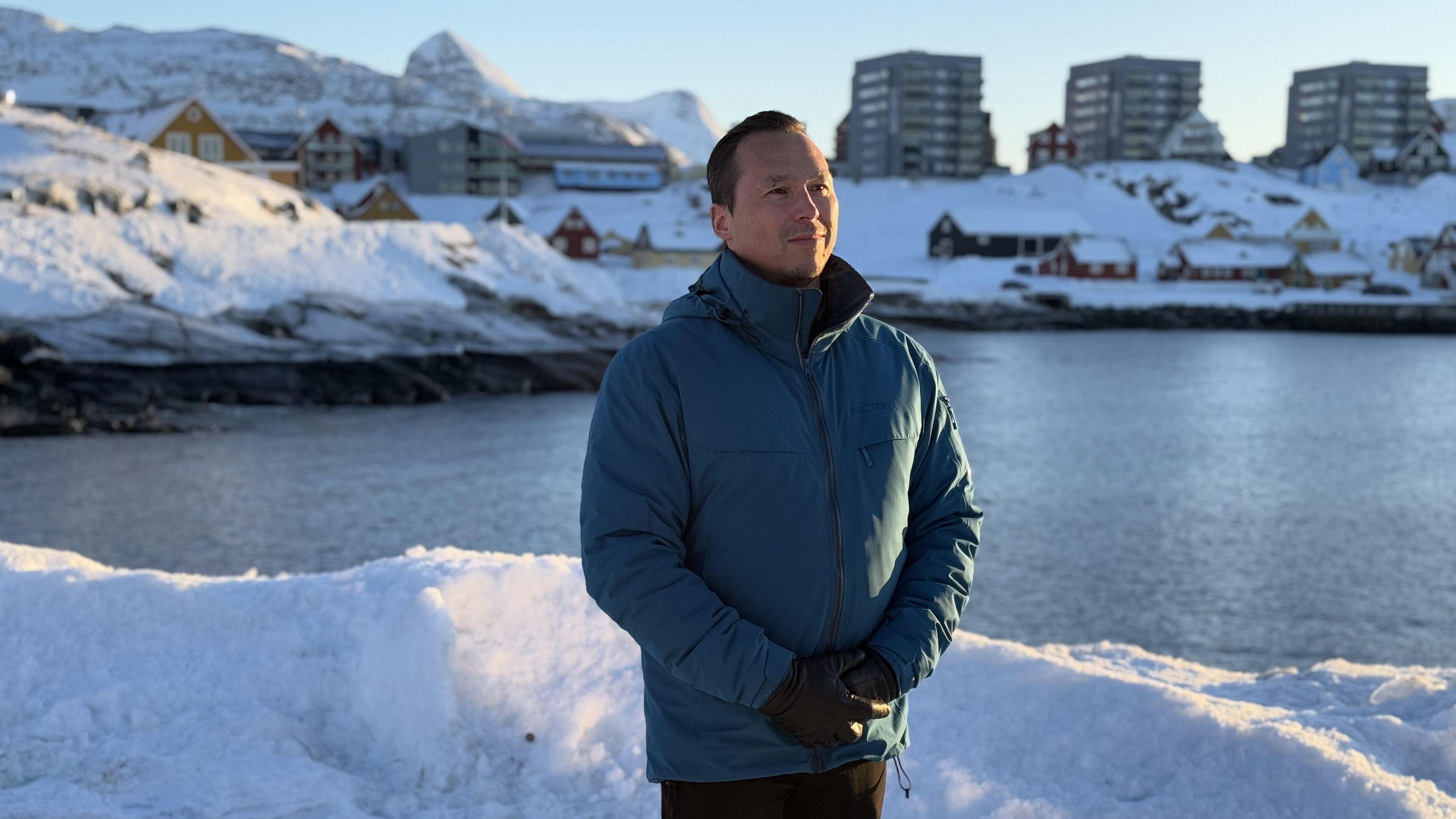 Kuno Fencker standing beside a body of water wearing a blue jacket and sun shining on side of his face