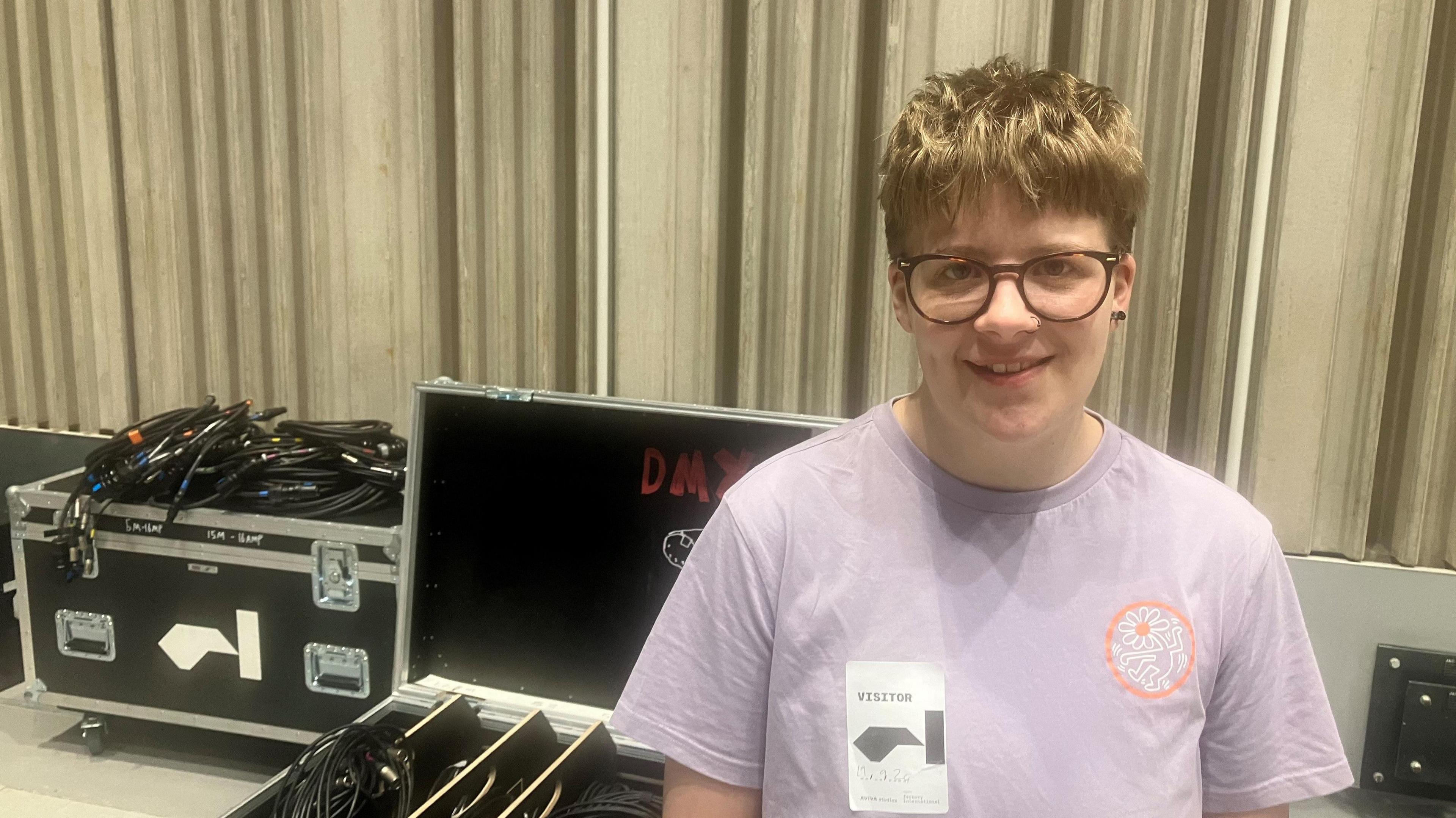 Factory Academy graduate Fletcher Davies-Rushton wearing a purple t-shirt stood next to some technical equipment backstage.