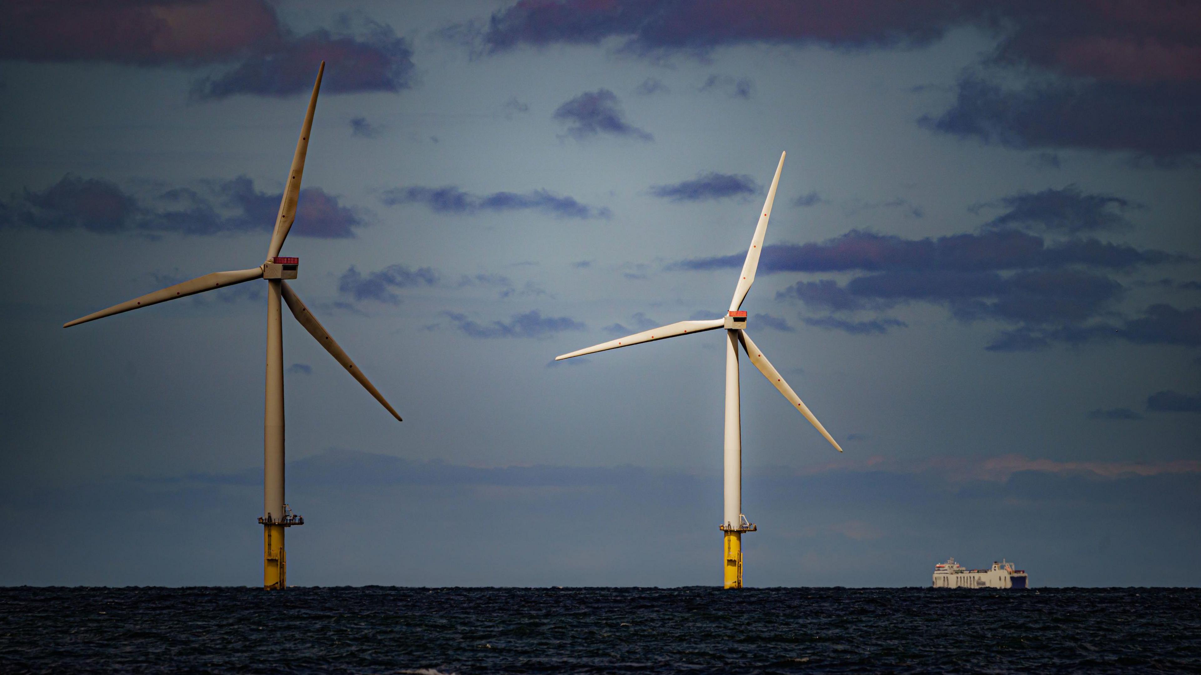 Wind turbines in sea with ship alongside