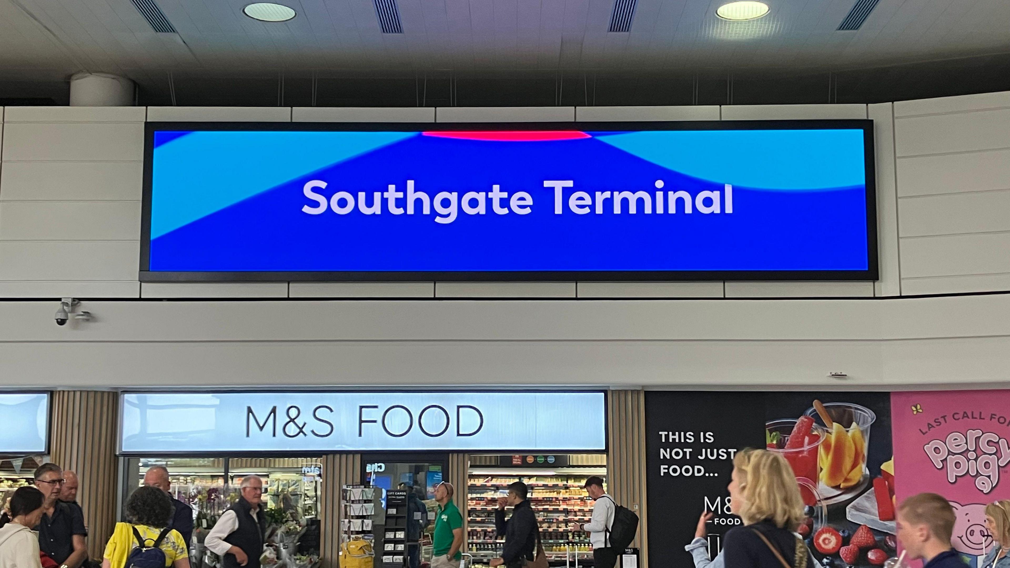 A large electronic sign at Gatwick Airport, over a supermarket, reading Southgate Terminal in white text