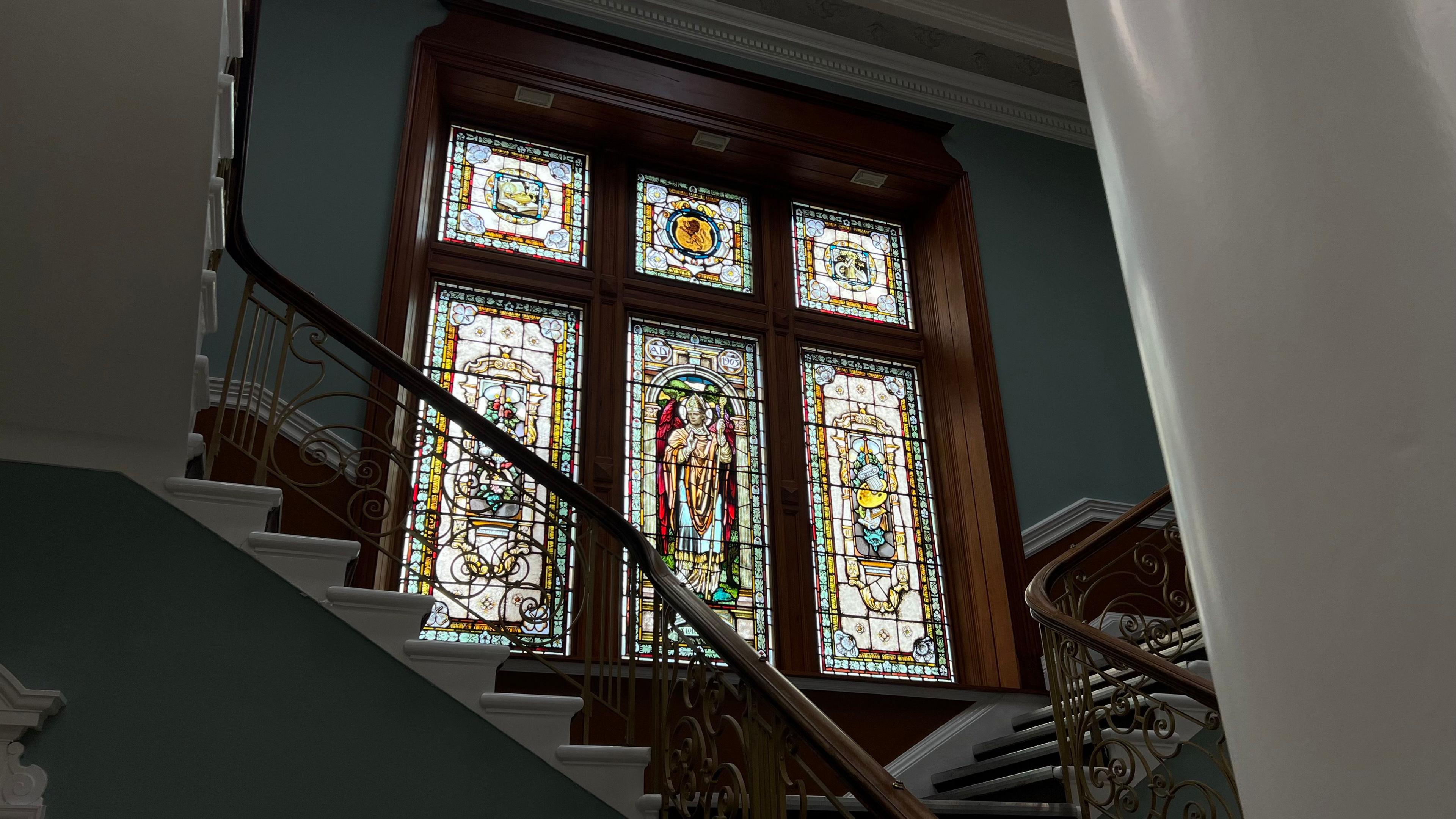 Six stained glass windows - the centre window features an image of a religious figure 