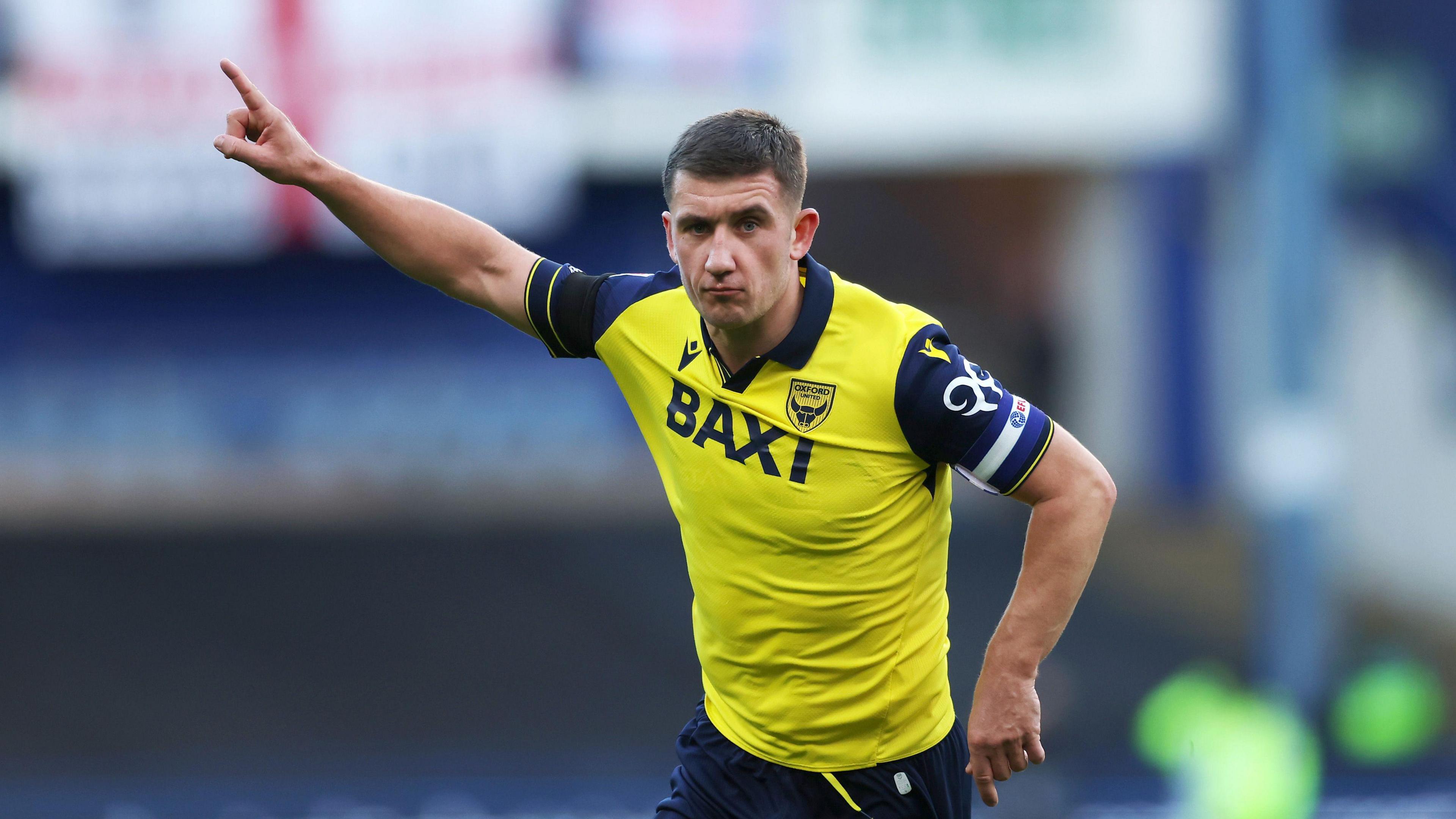 Oxford Utd skipper Cameron Brannagan running with right arm and finger in the air