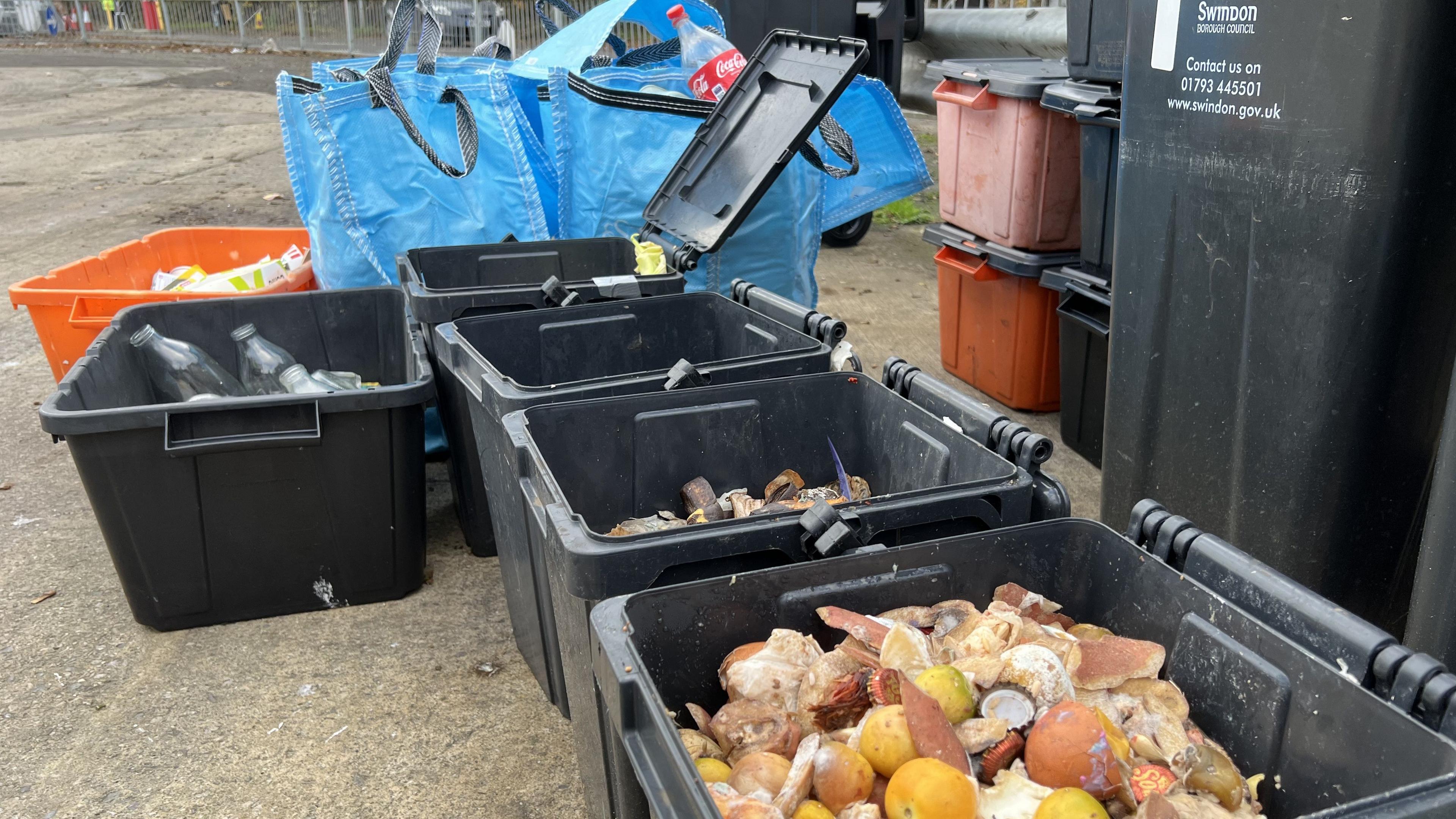 Multiple recycling bins, boxes and bags with a close up on a food caddie filled with food waste.