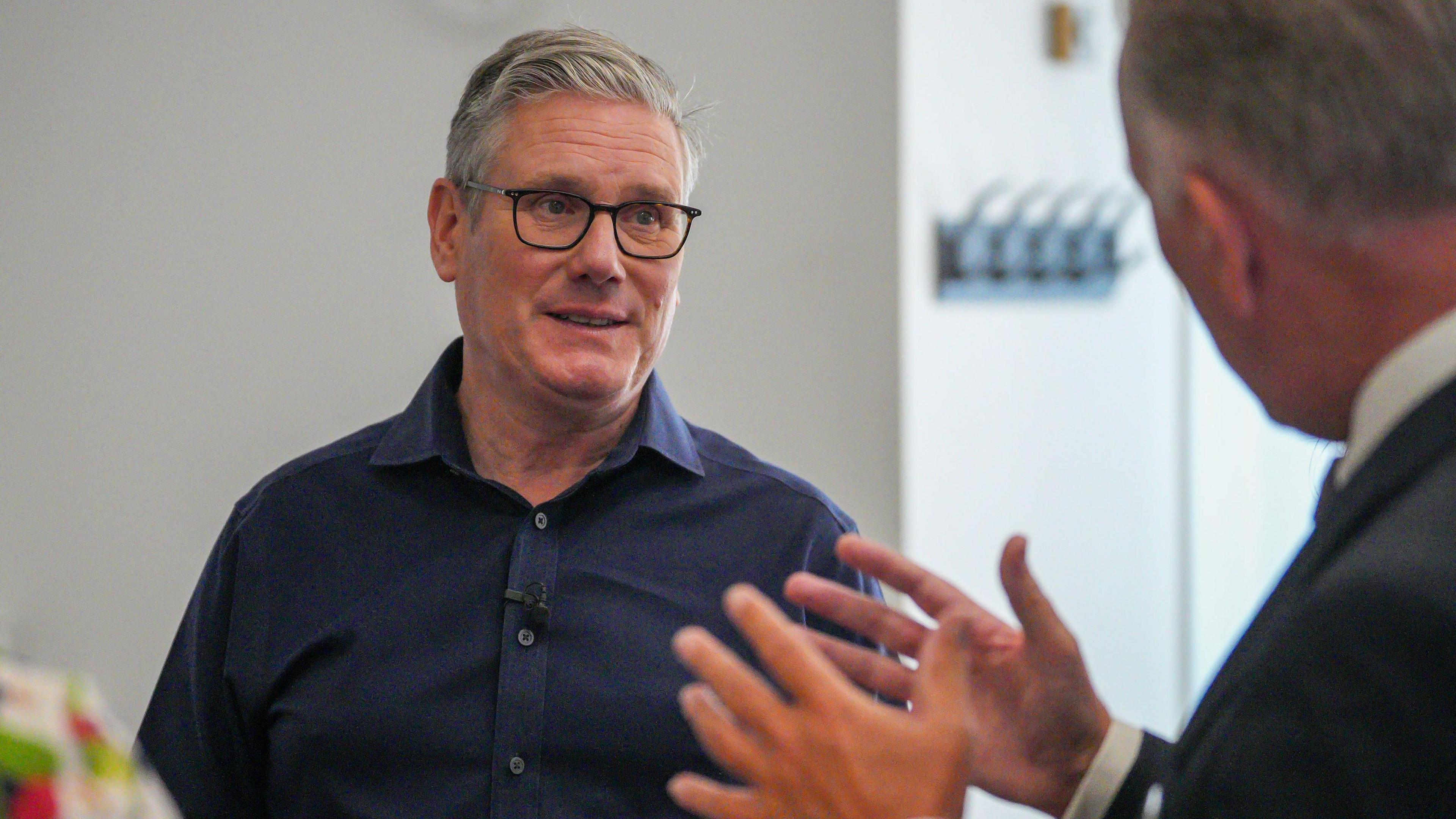 Library image of Sir Keir Starmer during a visit to Milton Keynes Central Library in Buckinghamshire earlier this month. He has short grey hair and is wearing black glasses and a navy shirt. He is in conversation with another man who can be seen in the foreground wearing a suit.