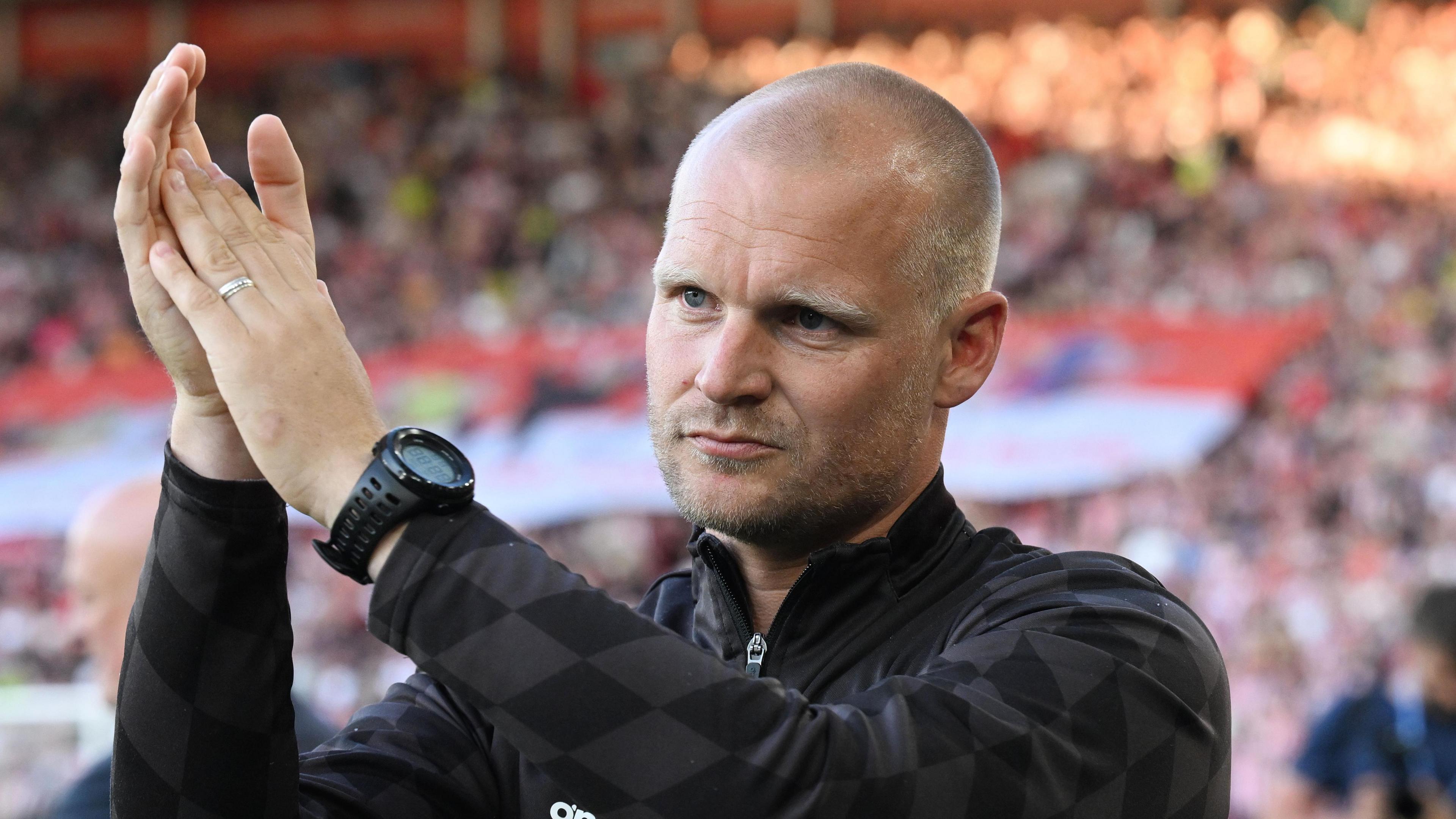 Liam Manning applauding from the touchline.