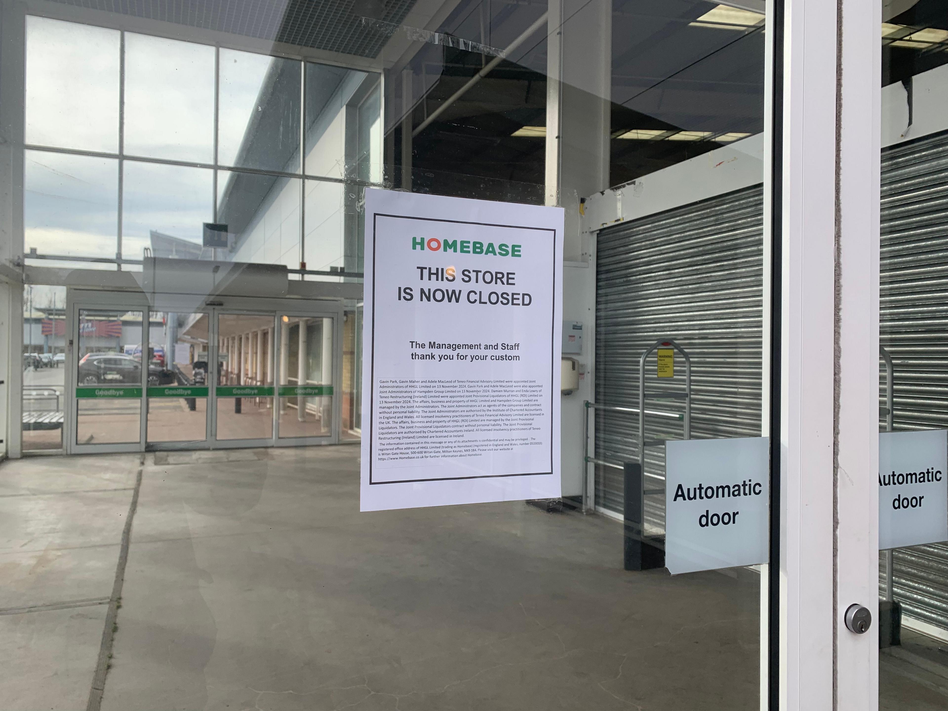 A sign on a glass sliding automatic door informs customers that the Homebase store is now closed