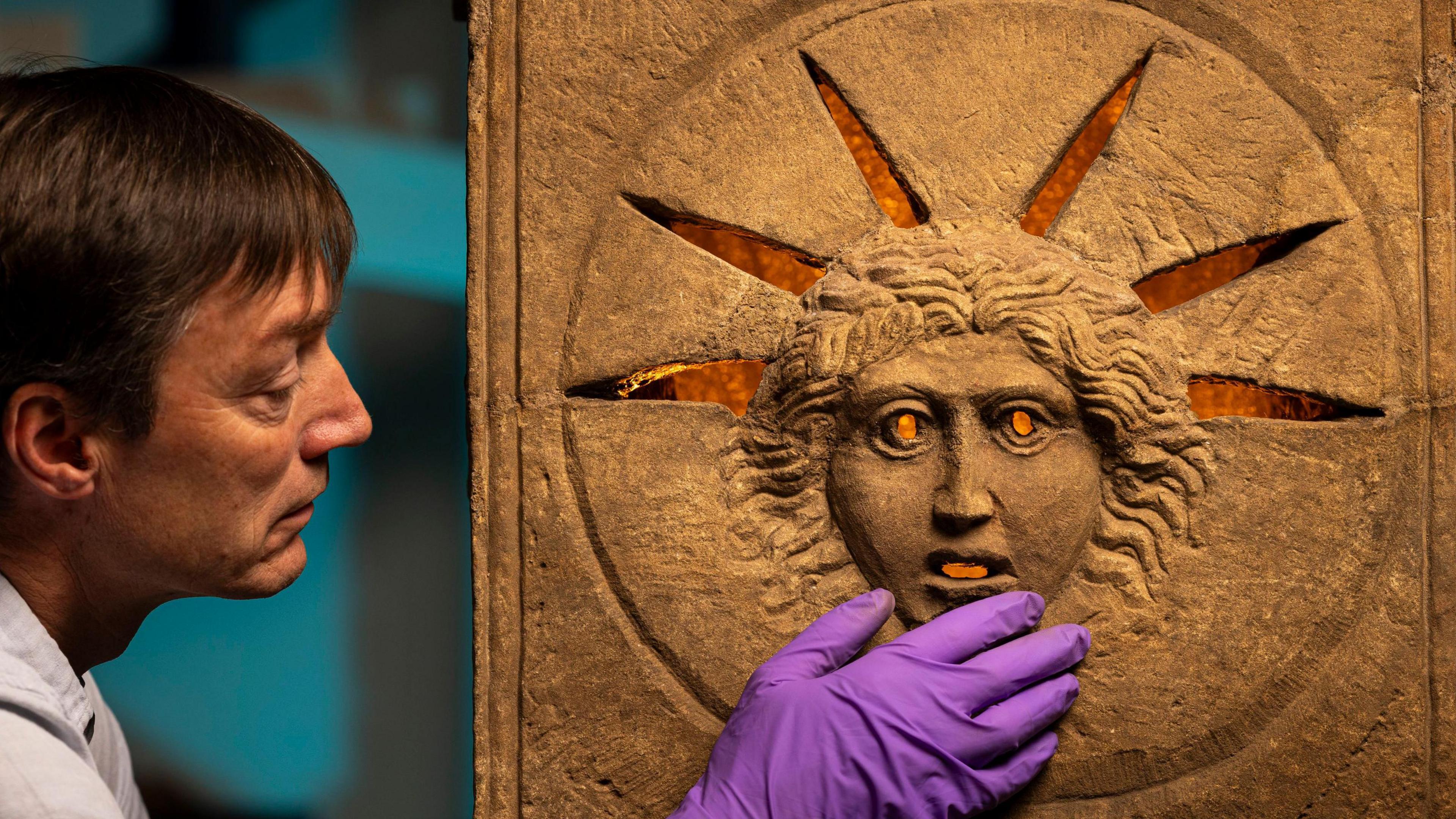 one of the historians touching the altar, which has a face lit from behind.