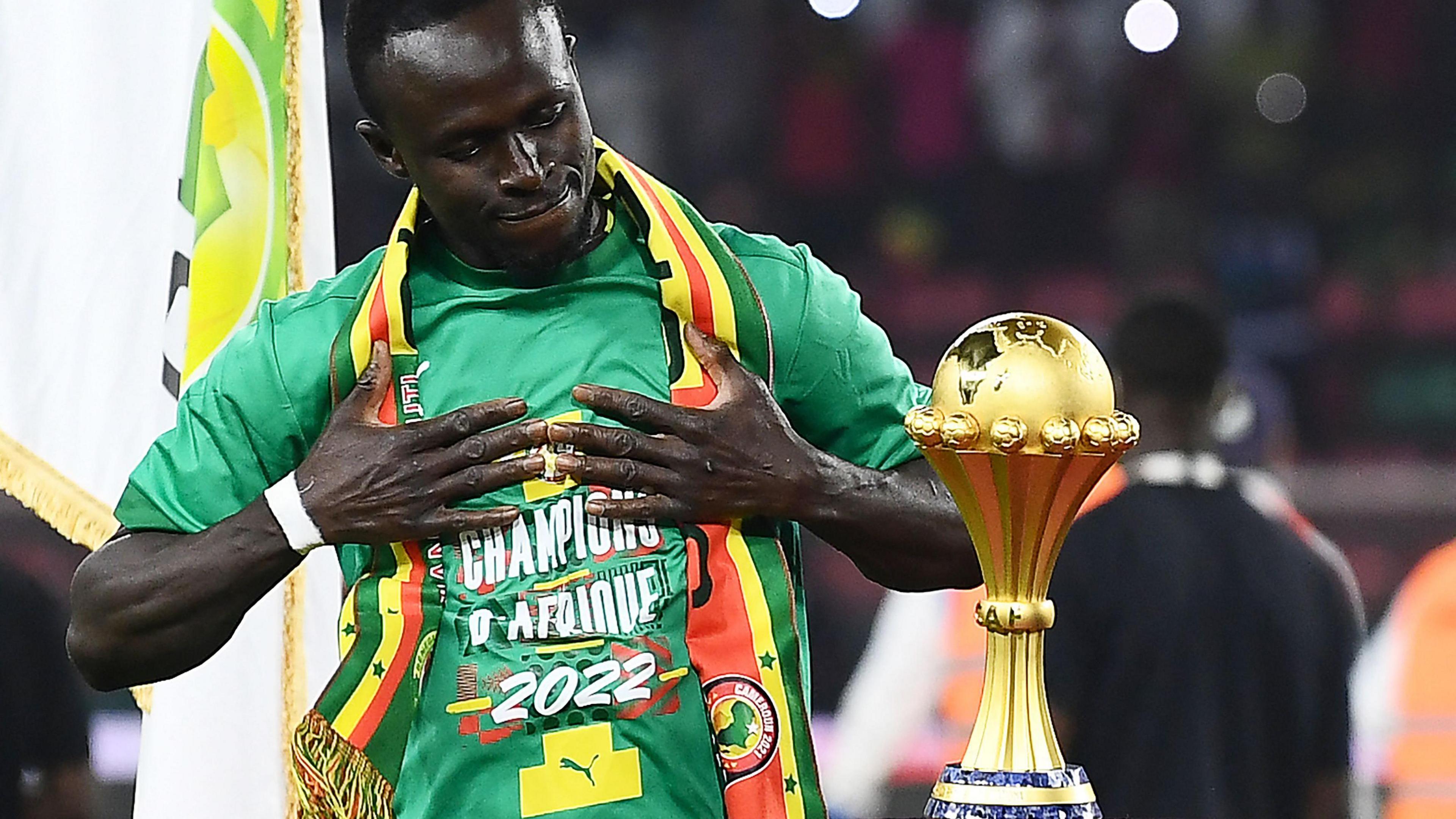 Sadio Mane holds his hands to his chest as he admires the Africa Cup of Nations trophy