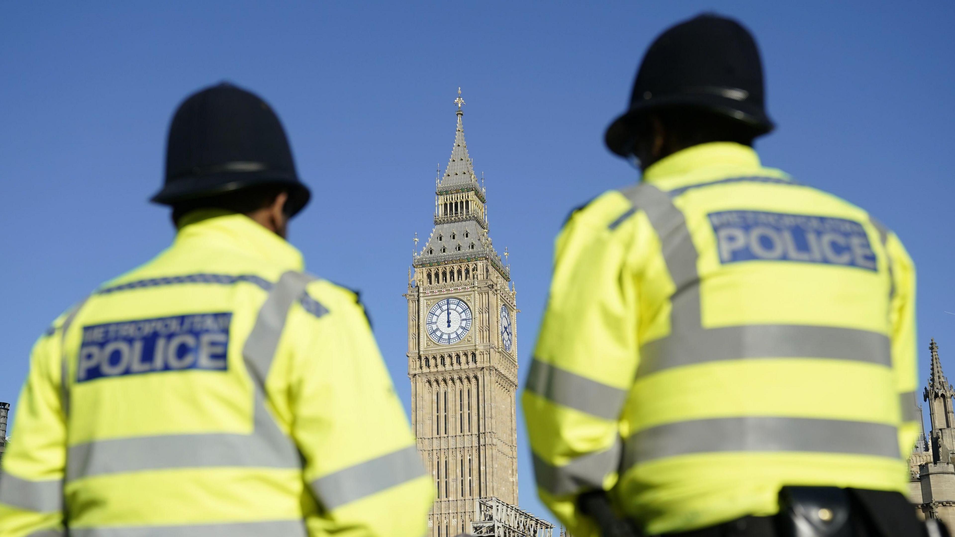Two police officers with their back turned, looking towards Big Ben