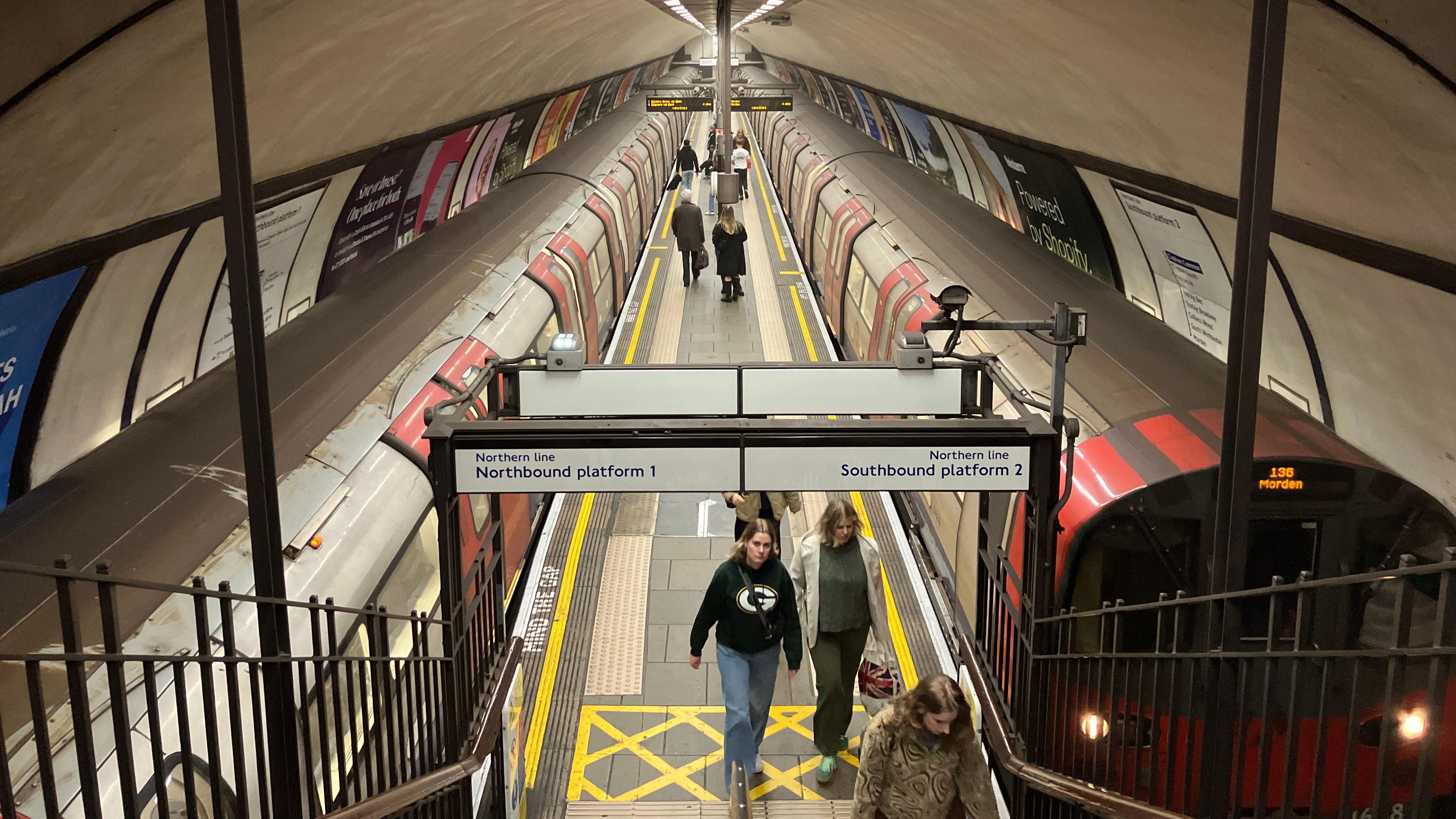 Platform at Clapham Common station shows two Tube trains and passengers walking along it